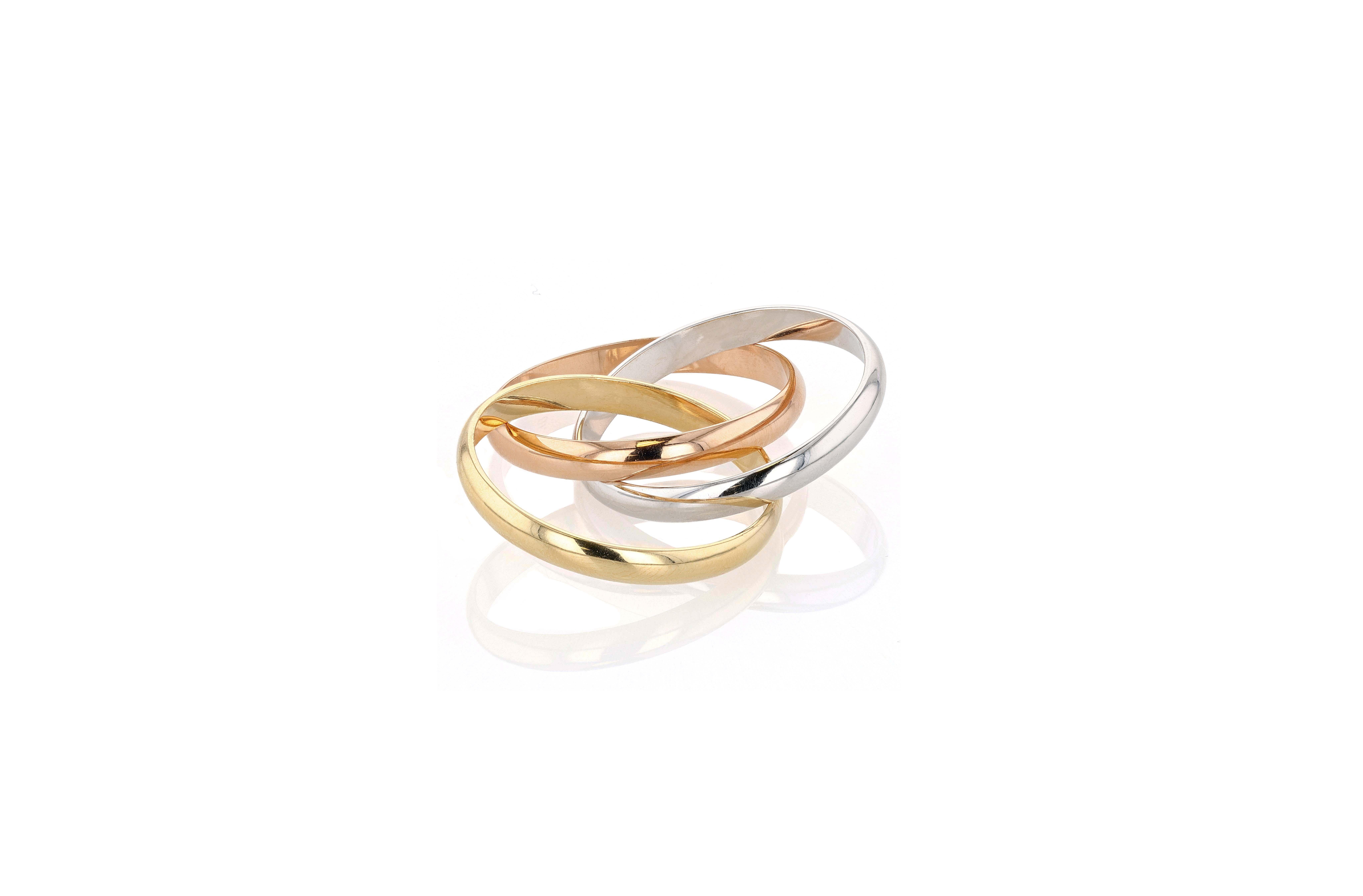 An 18 karat yellow, white, and rose gold Cartier Trinity rolling ring composed of three interlocking gold bands, each 3mm in thickness. 

Cartier Trinity was created in 1924, allegedly at the behest of Jean Cocteau who was obsessed with the rings of