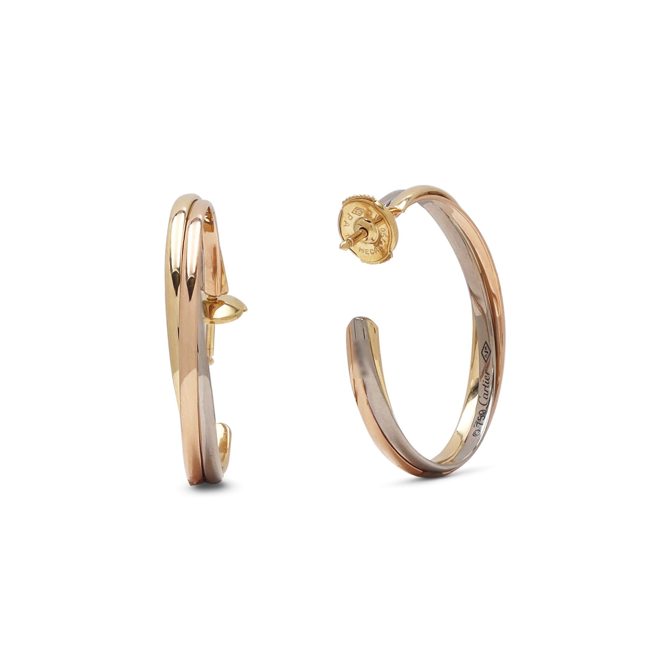 Authentic Cartier 'Trinity' hoop earrings are comprised of interlocking bands of 18 karat yellow, rose, and white gold. The earrings measure 30mm (1.2 inches) in length. Signed Cartier, 750, with serial number and hallmarks. The earrings are