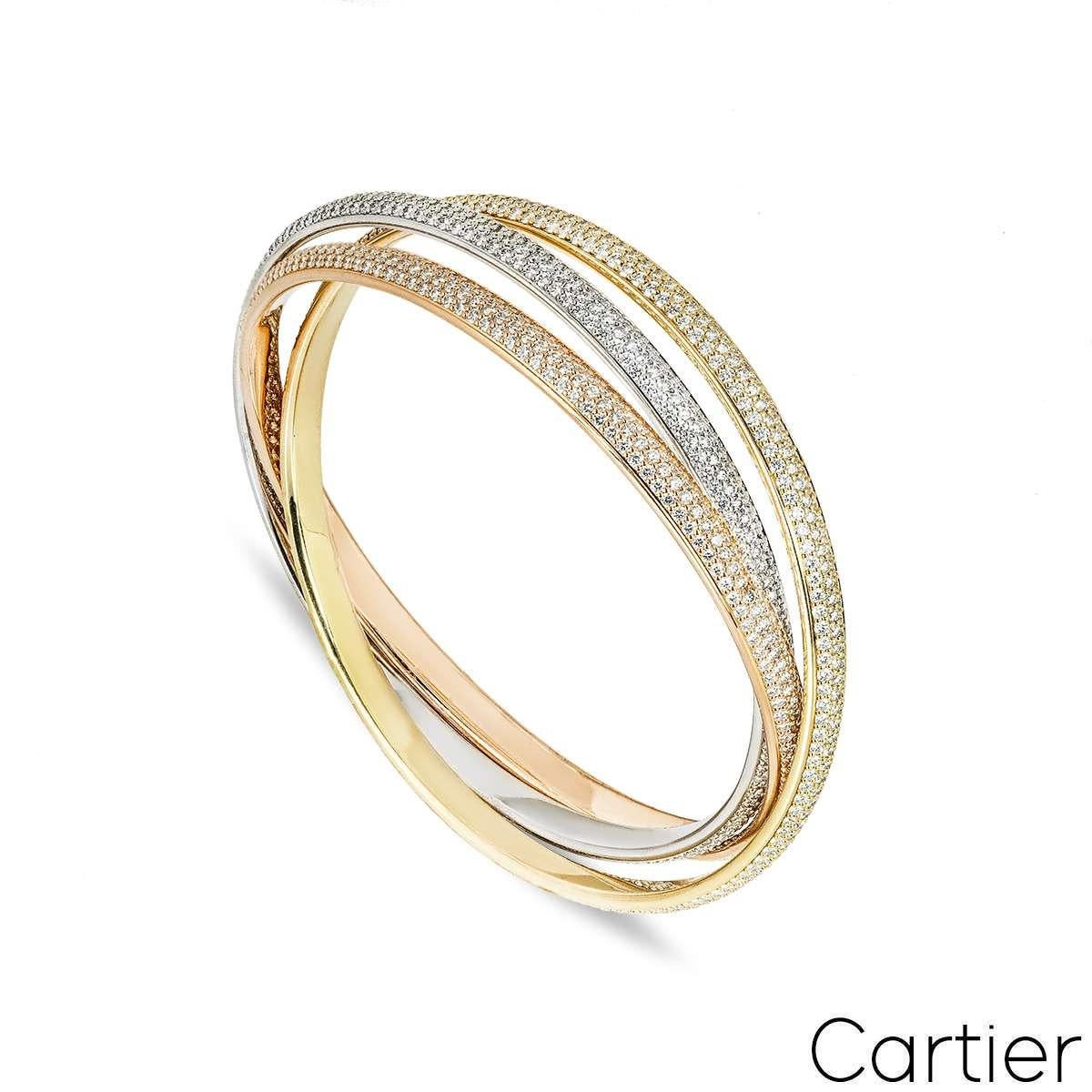 Un brazalete tricolor Cartier de 18 quilates de la colección Trinity. El diseño presenta tres bandas entrelazadas de oro blanco, rosa y amarillo de 18 quilates de 5 mm, cada una completamente engastada con tres filas de diamantes redondos talla
