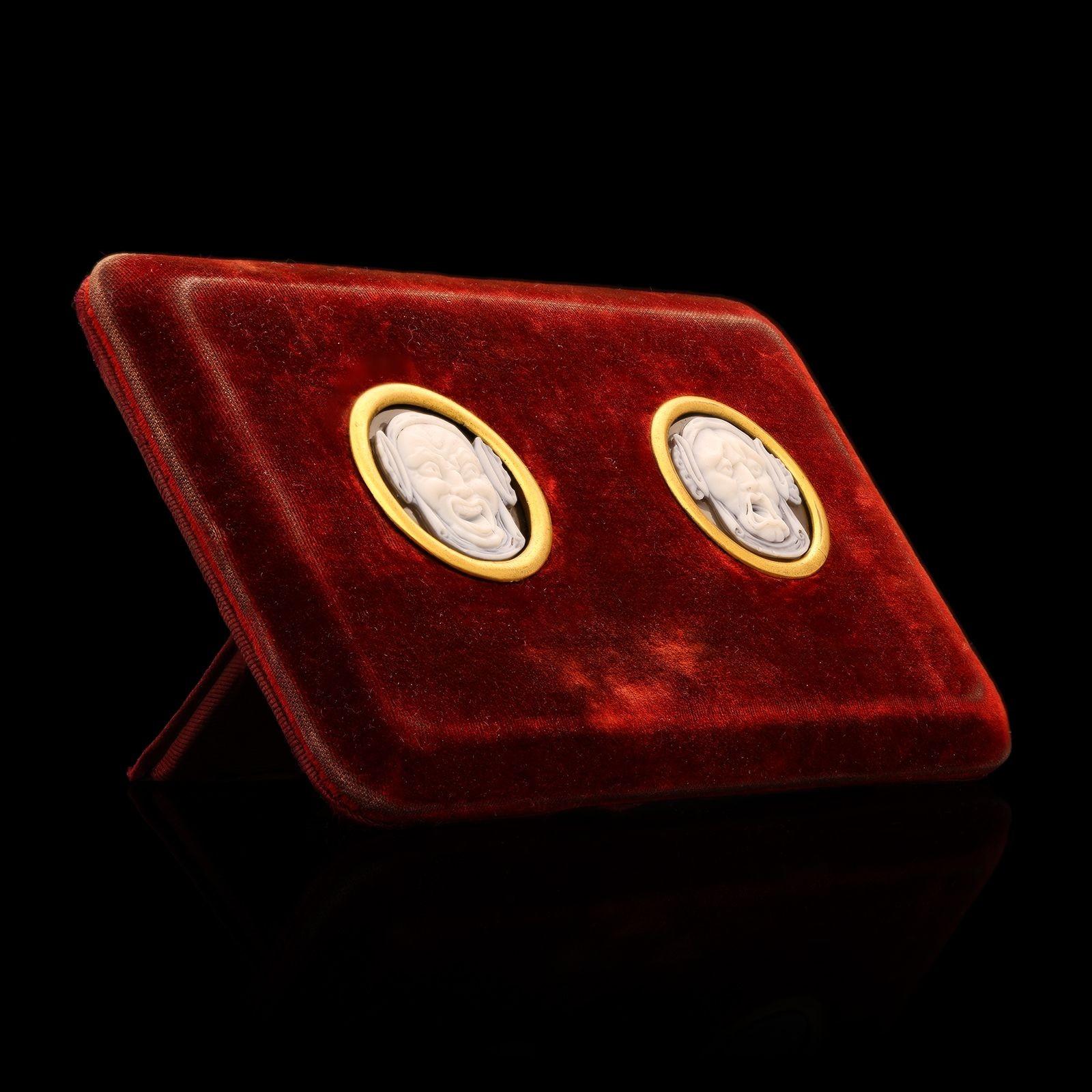 A rare and unusual pair of cameos framed by Cartier, c.1870s, the two cameos carved from black and white banded agate hardstone and depicting ancient Greek theatre masks, one for tragedy and the other comedy, set into a red velvet custom made