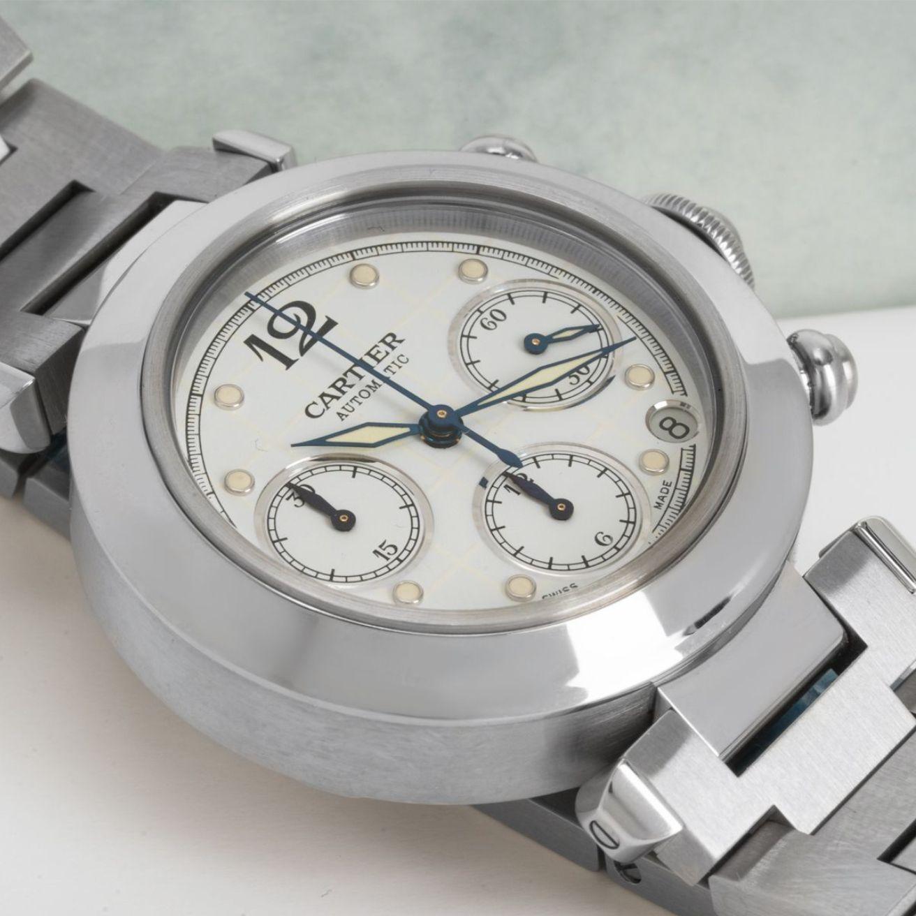 A NOS stainless steel Pasha Chronograph wristwatch by Cartier. Features a white dial with a date aperture, 3 chronograph counters and a stainless steel bezel as well as a crown cover and chronograph pushers.

Fitted with a sapphire glass, an