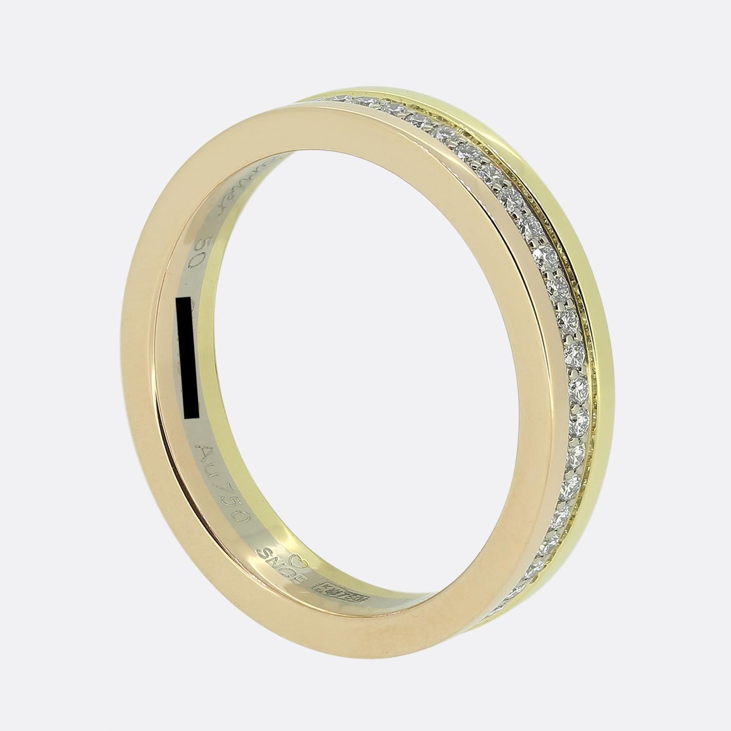 Aquí tenemos un anillo de oro de 18 quilates de la mundialmente conocida casa de joyas de lujo Cartier, con una única fila de diamantes redondos talla brillante. El diseño presenta un elegante engaste de canal con diamantes que rodean la banda por
