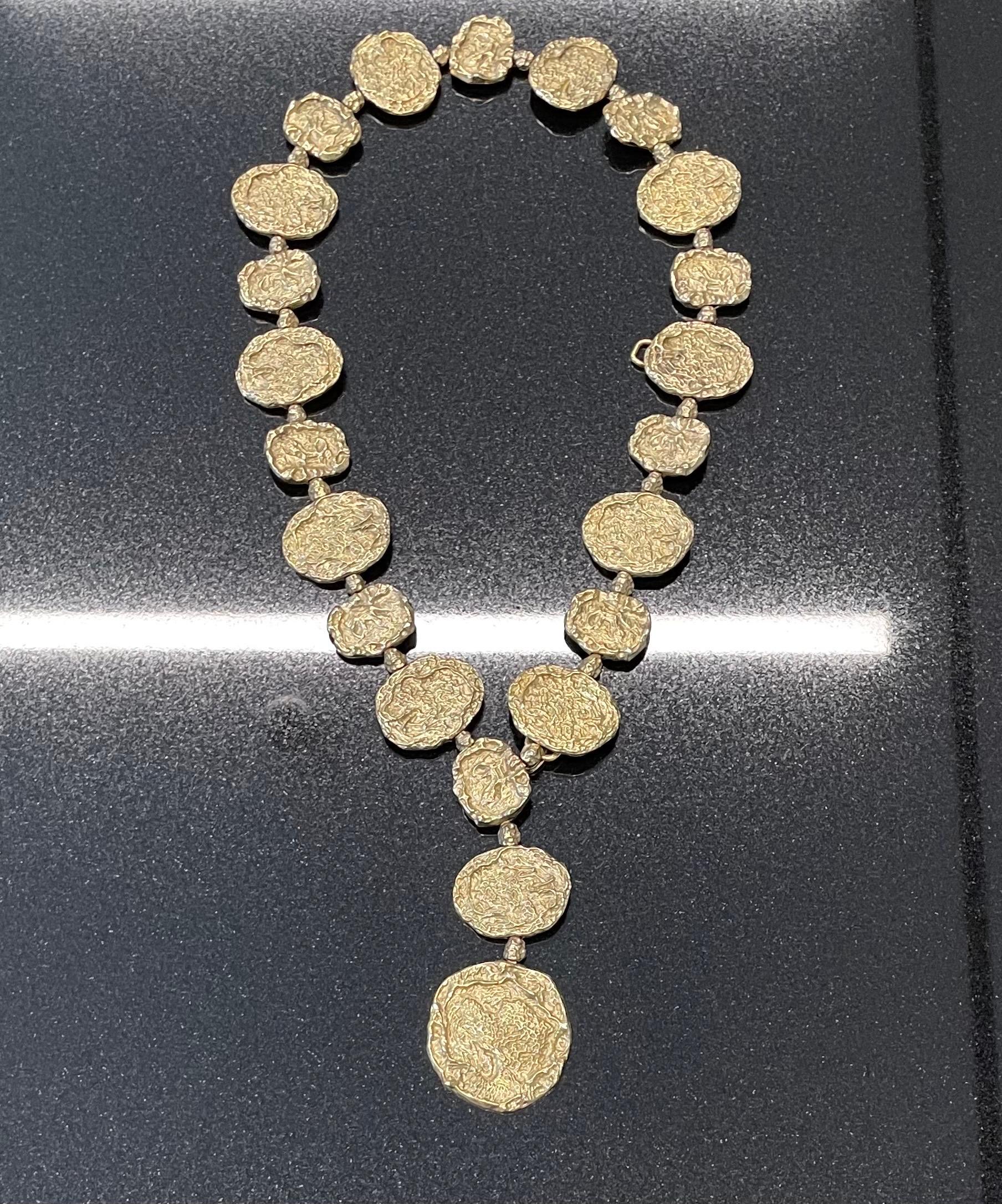 This Cartier Vermeil (gold on sterling silver) necklace is comprised of textured circular discs in the brutalist style, designed circa 1970. The second image shows Jacqueline Kennedy Onassis wearing another example of this design as a belt while on