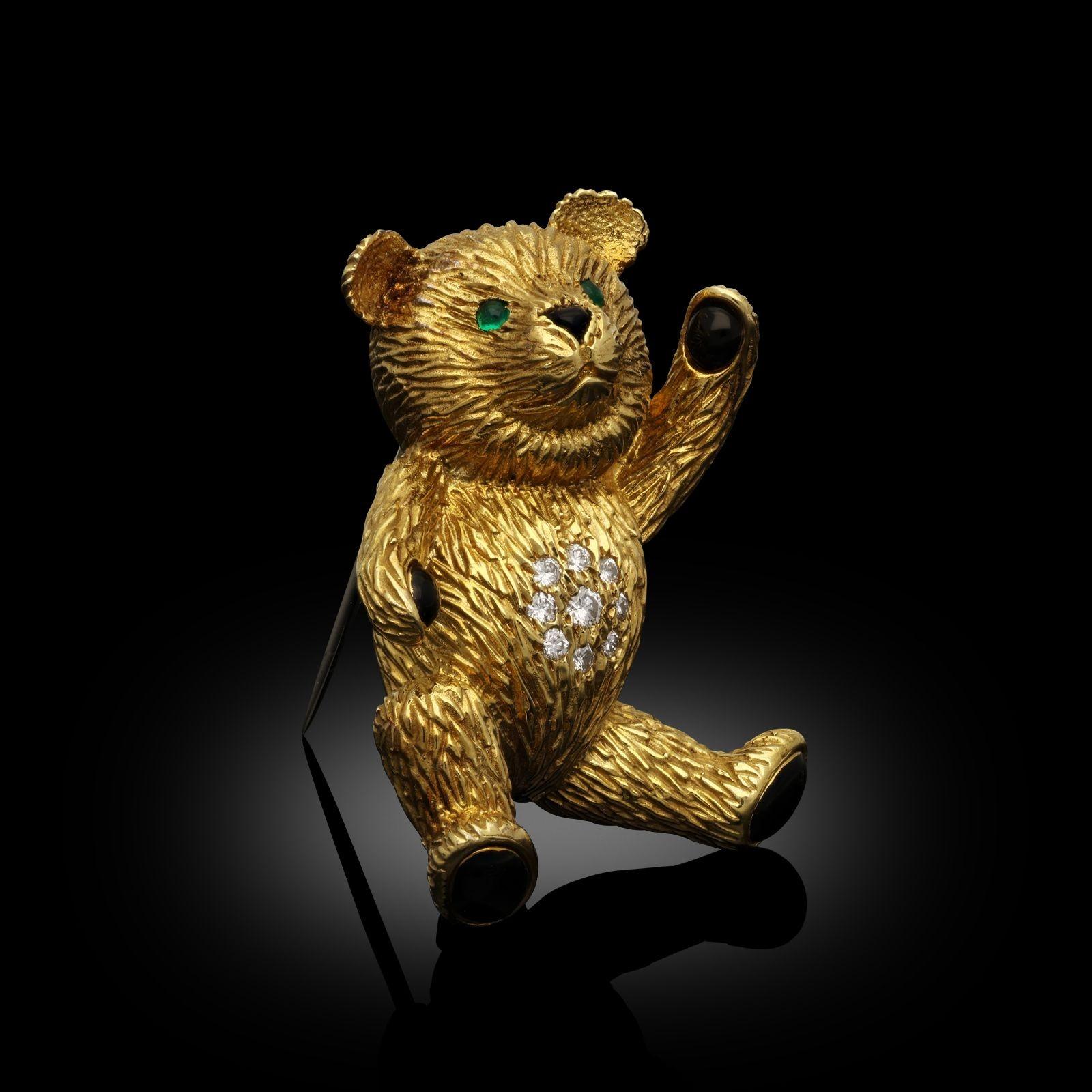 A vintage teddy bear brooch in 18ct yellow gold by Cartier, 1987. The brooch is designed as a seated teddy bear with round brilliant cut diamonds set into the belly and the paw pads and nose of the bear accented with polished black onyx, the eyes