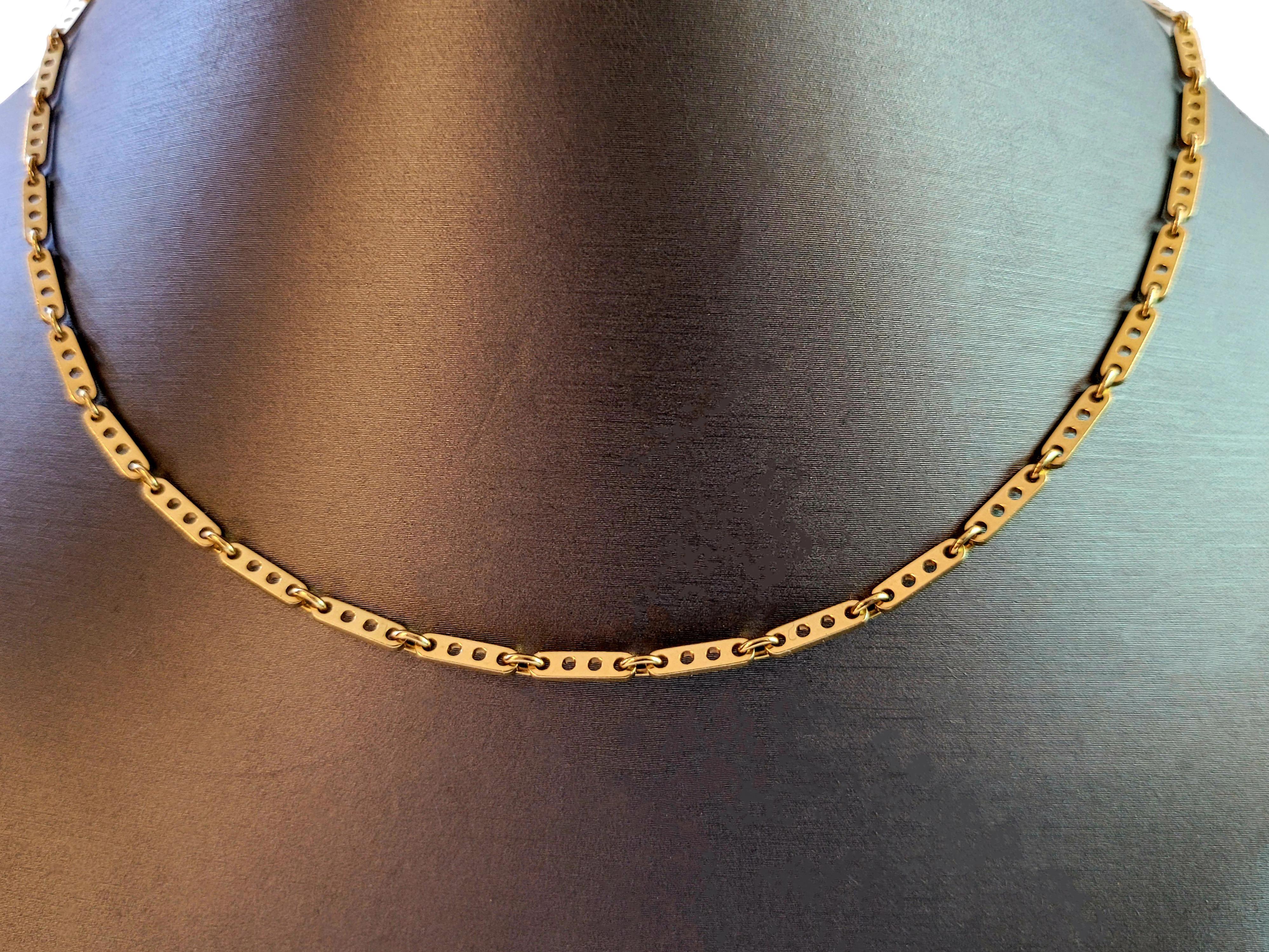 Questa elegante collana vintage di Cartier (anni '90 circa) presenta elementi a forma di barretta in oro giallo 18 carati intrecciati con motivi circolari tagliati. I lingotti d'oro rettangolari, collegati da una piccola maglia rotonda, hanno una