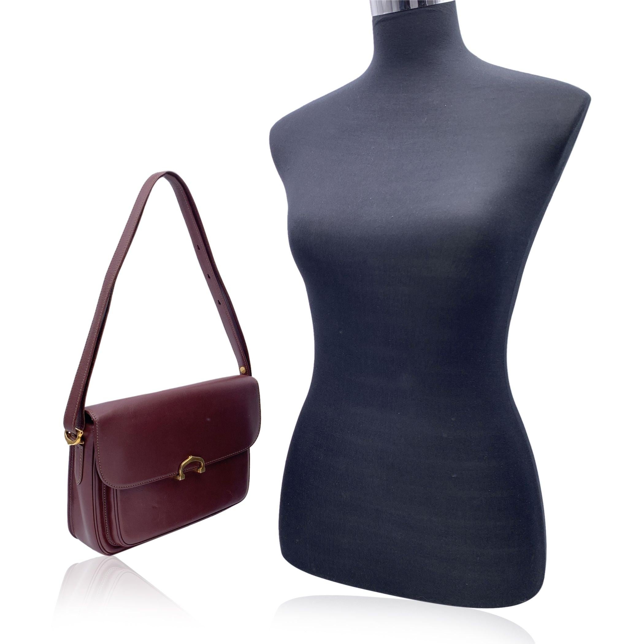 CARTIER Paris vintage shoulder bag in Burgundy genuine leather. Gold metal hardware. . 1 open pocket under the flap. Burgundy lining with Cartier logos 1 side zip pocket and D-ring inside. Adjustable shoulder strap (the bag can be worn on the