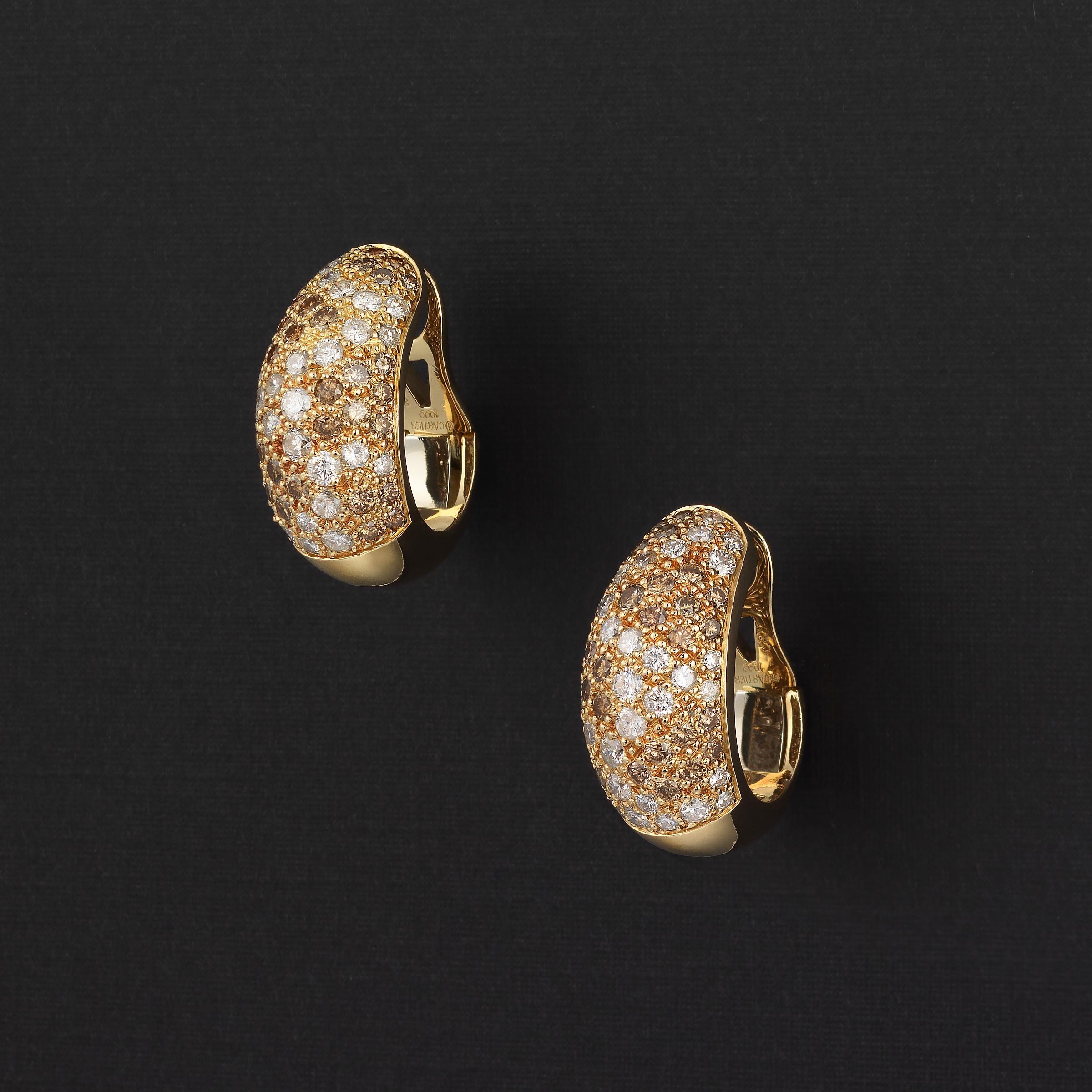 A glittering vintage pair of Cartier bombe earrings showcasing approximately 4 carats of white and cognac - brown colored diamonds, all pave-set in 18 karat yellow gold. The earrings are masterfully crafted by Cartier and their gently curving bombe