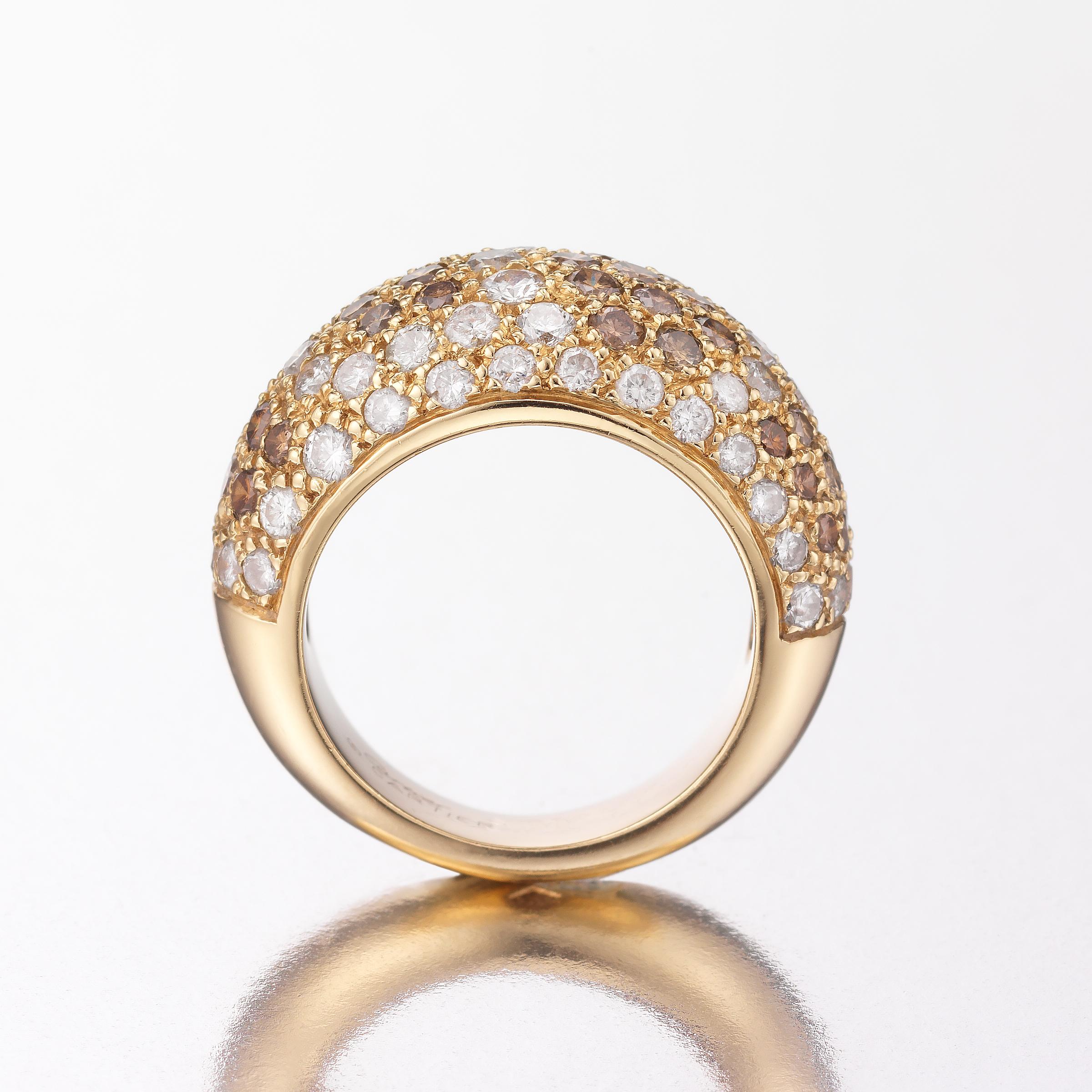 A glittering Cartier bombe ring showcasing approximately 3.5 carats of white and cognac - brown colored diamonds, all pave-set in 18 karat yellow gold. The ring is masterfully crafted by Cartier and its gracefully curving bombe shape allows added