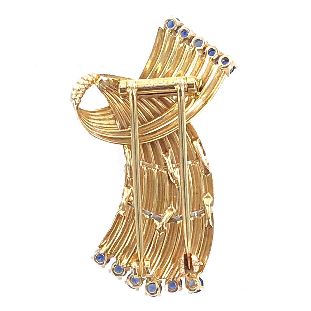 1960's Cartier diamond blue sapphire ribbon pin. This elegant brooch features 6 round brilliant cut diamonds (.50 carat total weight) graded F color and VS clarity. Sixteen bright blue sapphires equal approximatley 2.08 carat total weight. Signed