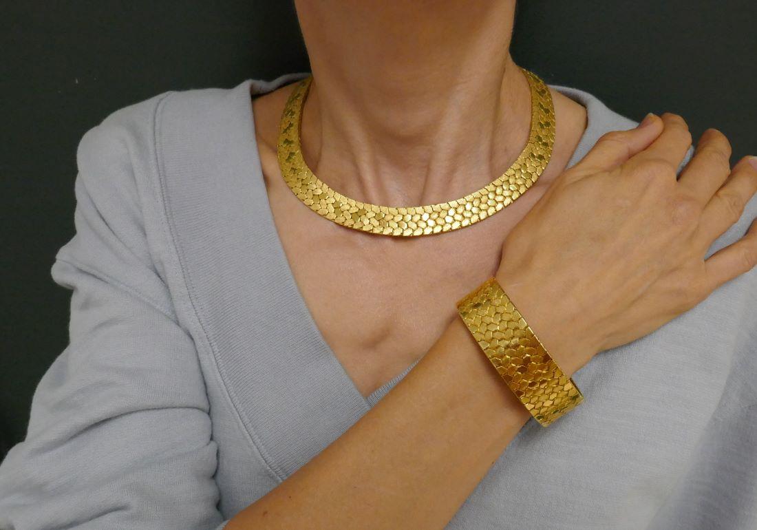 A Cartier vintage 18k gold bracelet and necklace set. The pieces are crafted from tightly woven gold bands. Textured and polished gold create a geometric pattern. 
The Cartier gold bracelet consists of six rows, and the necklace is slightly thinner,
