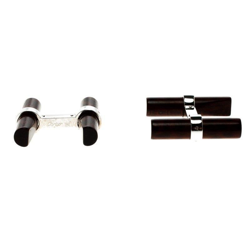 These Santos De Cartier cufflinks by Cartier sets the benchmark for innovation and excellence. Two beautiful wood bars are wonderfully held by 18k white gold. The bars are interchangeable and the pair comes with the brand label engraved on them. All