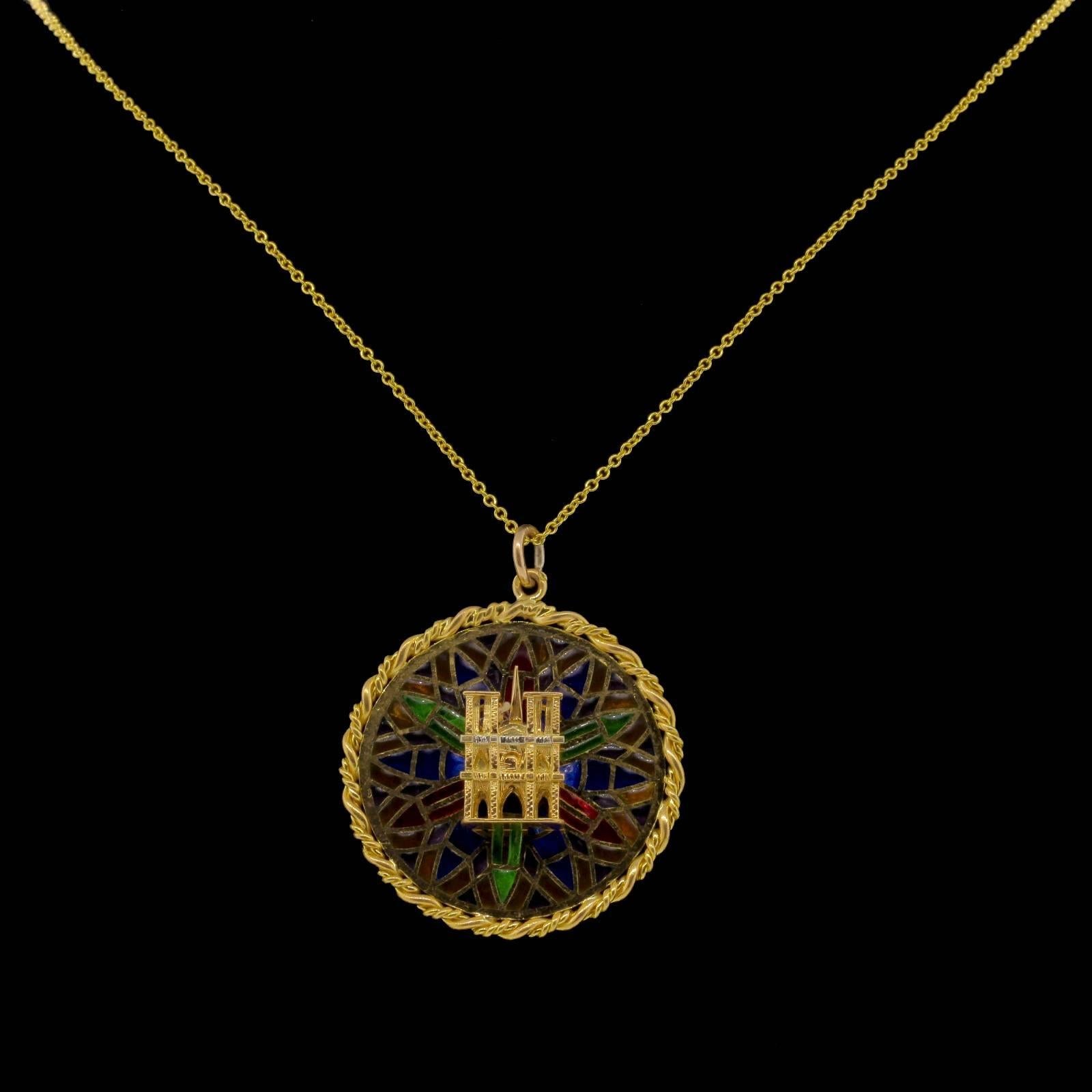 This vintage, Cartier French 18KT round charm/pendant features a luminous multicolor Plique-a-jour enamel, and centers a three dimensional representation of the iconic  Notre Dame Cathedral facade.  An intertwined rope borders the pendant.  The bail