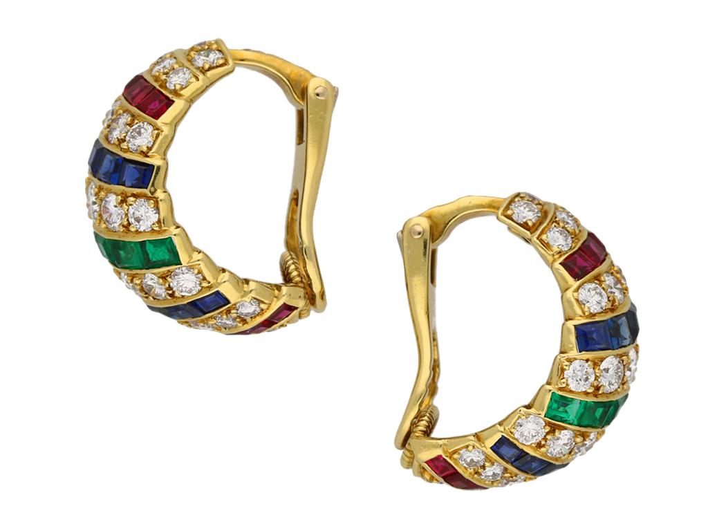 Ruby, sapphire, emerald and diamond earrings by Cartier London. A pair of yellow gold earrings, set with twenty baguette cut natural unenhanced rubies in open back channel settings with an approximate weight of 1.50 carats, twenty baguette cut