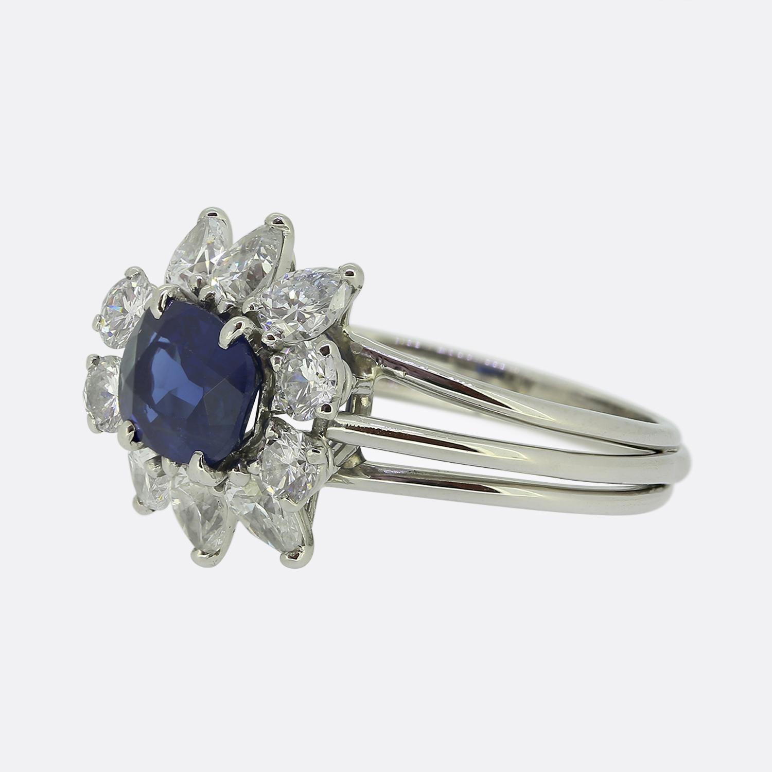Aquí tenemos un anillo precioso y poco común del diseñador de joyas de lujo Cartier. El anillo presenta un zafiro central talla cojín de un tono azul intenso perfecto. Alrededor del zafiro hay seis diamantes talla pera y cuatro redondos brillantes.