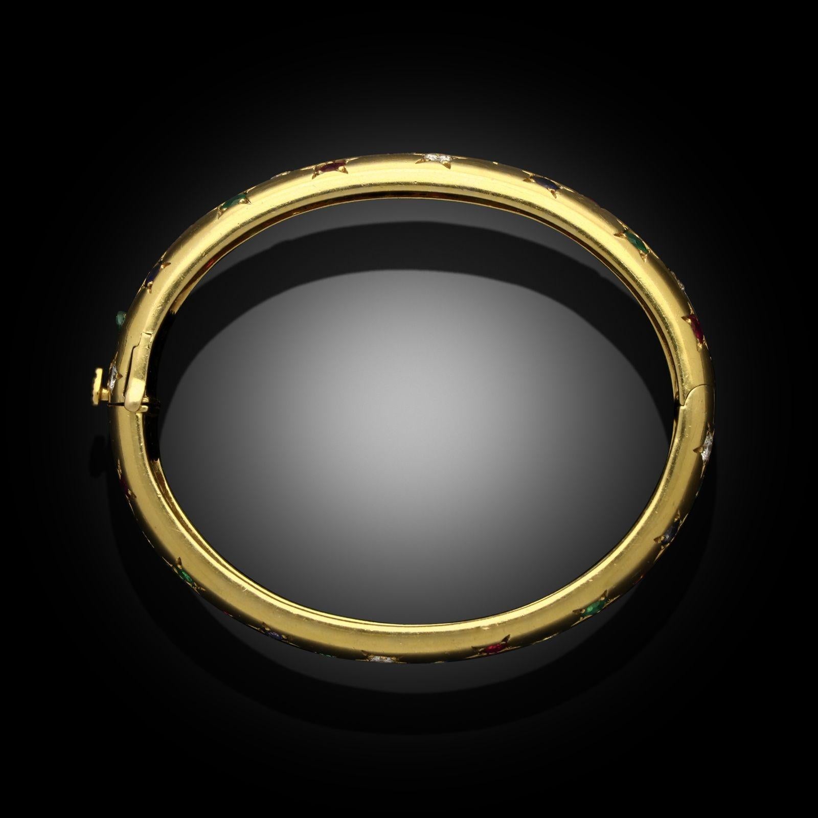 Ein Vintage-Armreif aus Gelbgold und mehrfarbigen Edelsteinen von Cartier Paris, um 1990. Der Armreif aus 18-karätigem Gelbgold hat ein abgerundetes Profil mit einer Kombination aus Diamanten, Rubinen, Saphiren und Smaragden, die jeweils in einer