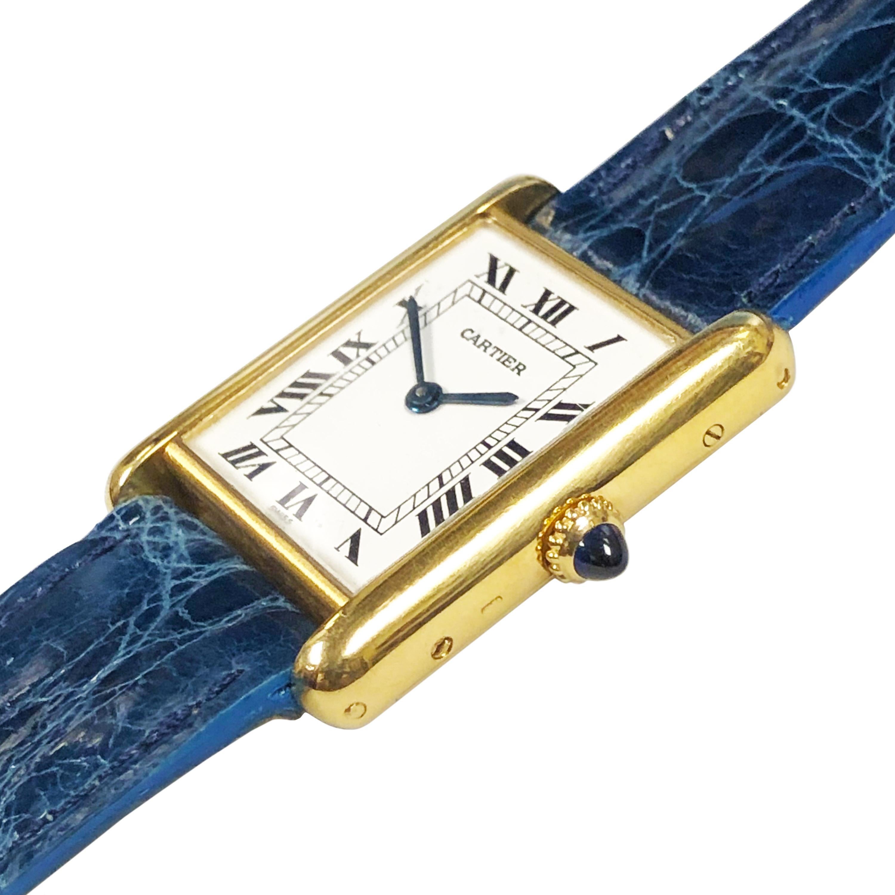 Circa 1980 Cartier Paris Classic tank watch, 30 X 23 MM 2 piece 18K Yellow Gold case, mechanical, manual wind 17 Jewel Cartier movement, White dial with Black Roman Numerals, sapphire Crown. New De Beers Paris Padded Blue Crocodile strap with Gold