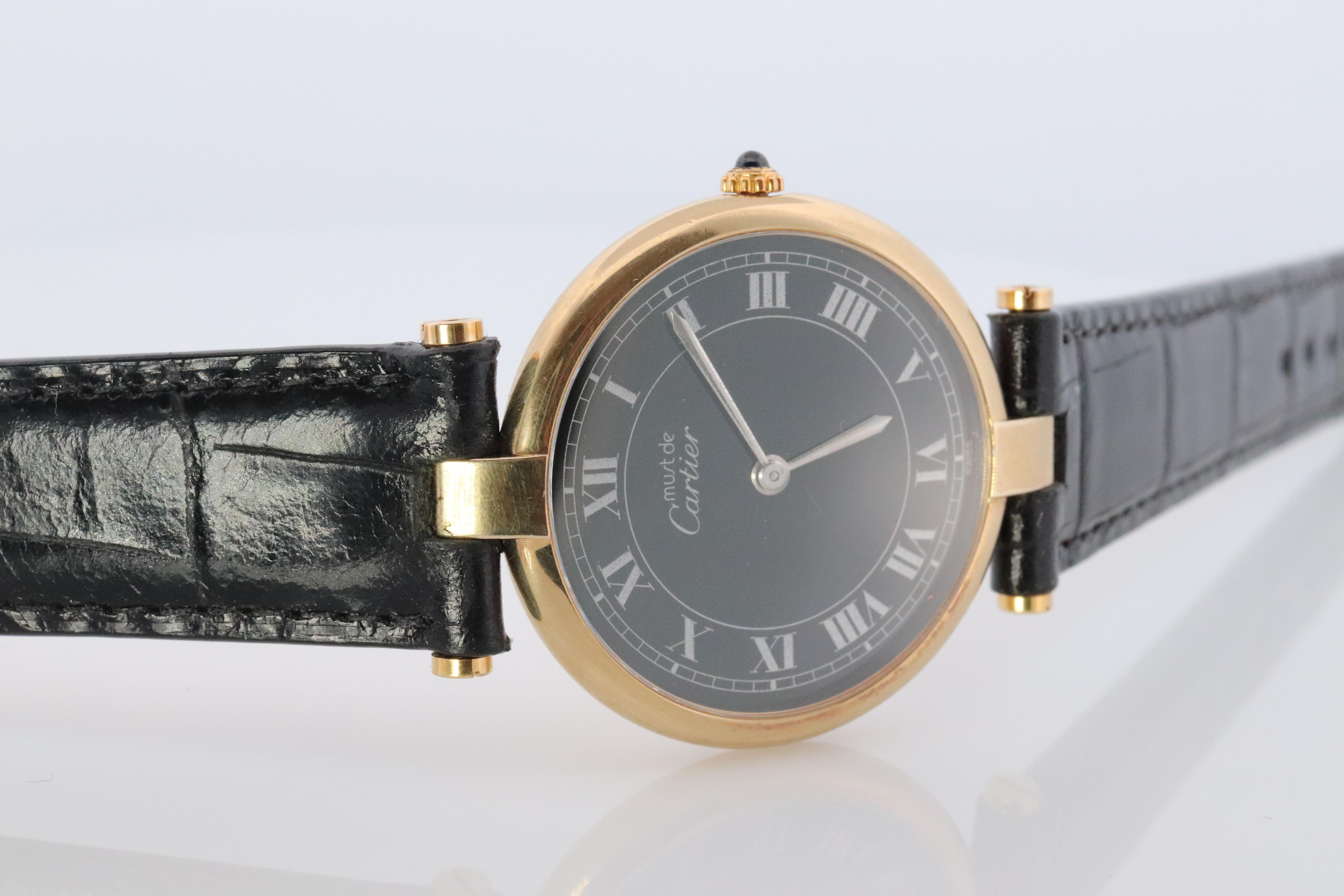 Genuine Cartier watch.

Vintage Must de Cartier 30mm Vendome

Black Dial with New Black Leather Band.

Sapphire Cabochon Crown.

Condition: Comes with Original Cartier case. Wear consistent with age. 

New battery installed.

Details:
30mm Round case