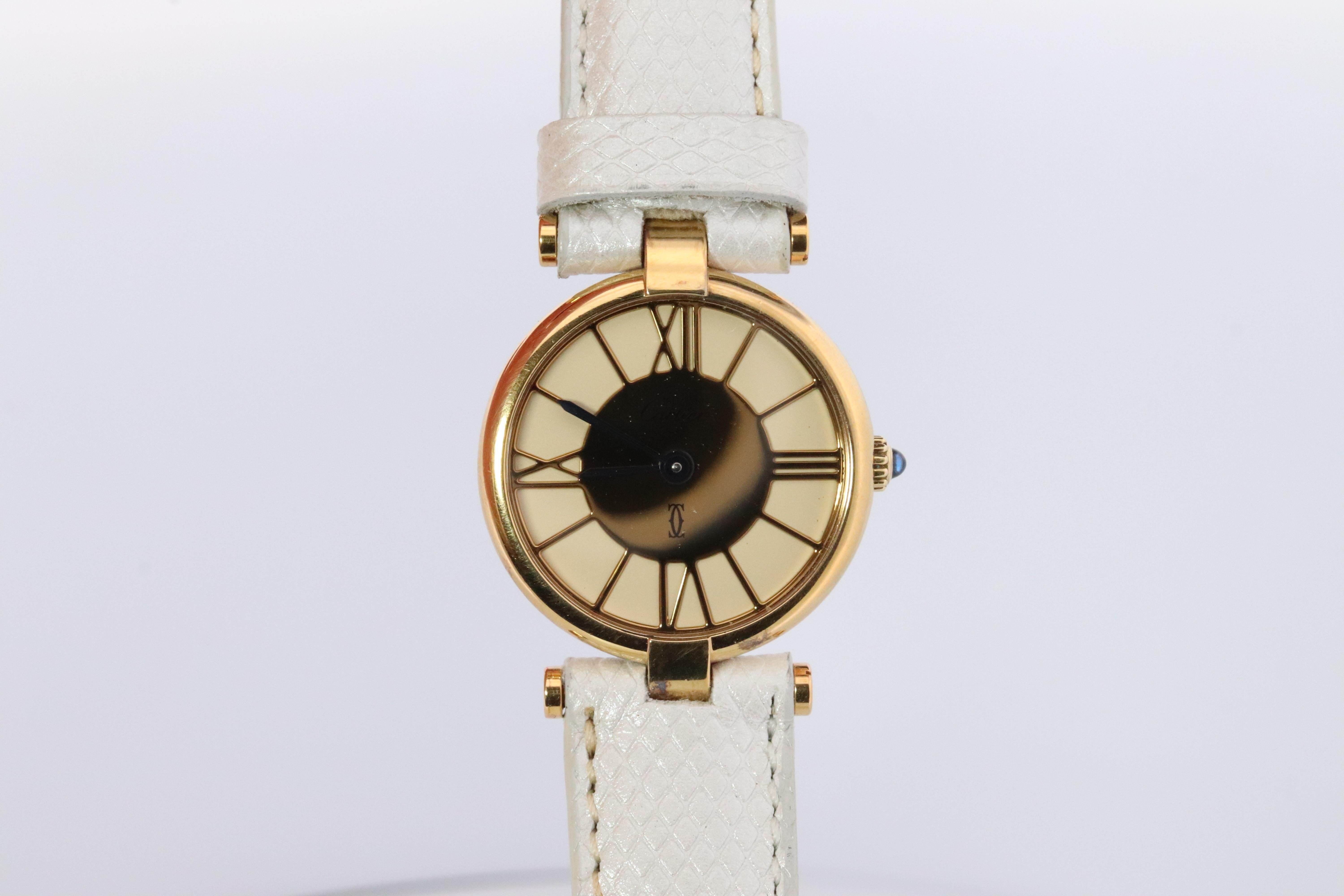 Echte Cartier Uhr.

Vintage Must de Cartier 24mm Vendome

Gold und weißes römisches Zifferblatt.

Saphir-Cabochon-Krone.

Zustand: Kommt mit Cartier Fall. Die Abnutzung entspricht dem Alter. Neu  Weißes Lederband. 

Neue Batterie
