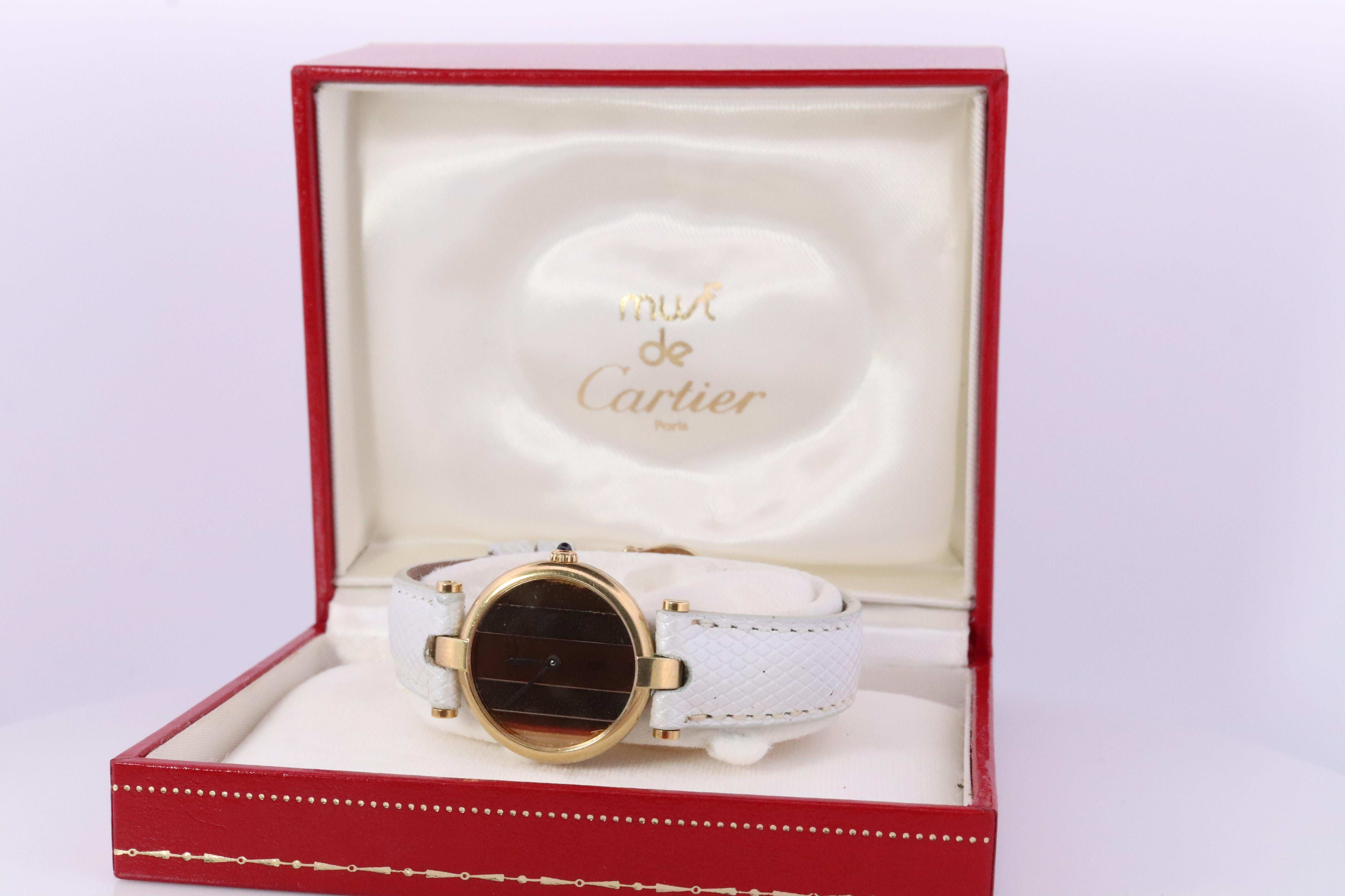 Genuine Cartier watch.

Vintage Must de Cartier Vendome

Trinity Tricolor Face. White, Gold and Rose Gold.

Sapphire Cabochon Crown.

Condition: Movement just serviced. Comes with Cartier case. Wear consistent with age. New Silver/White Genuine