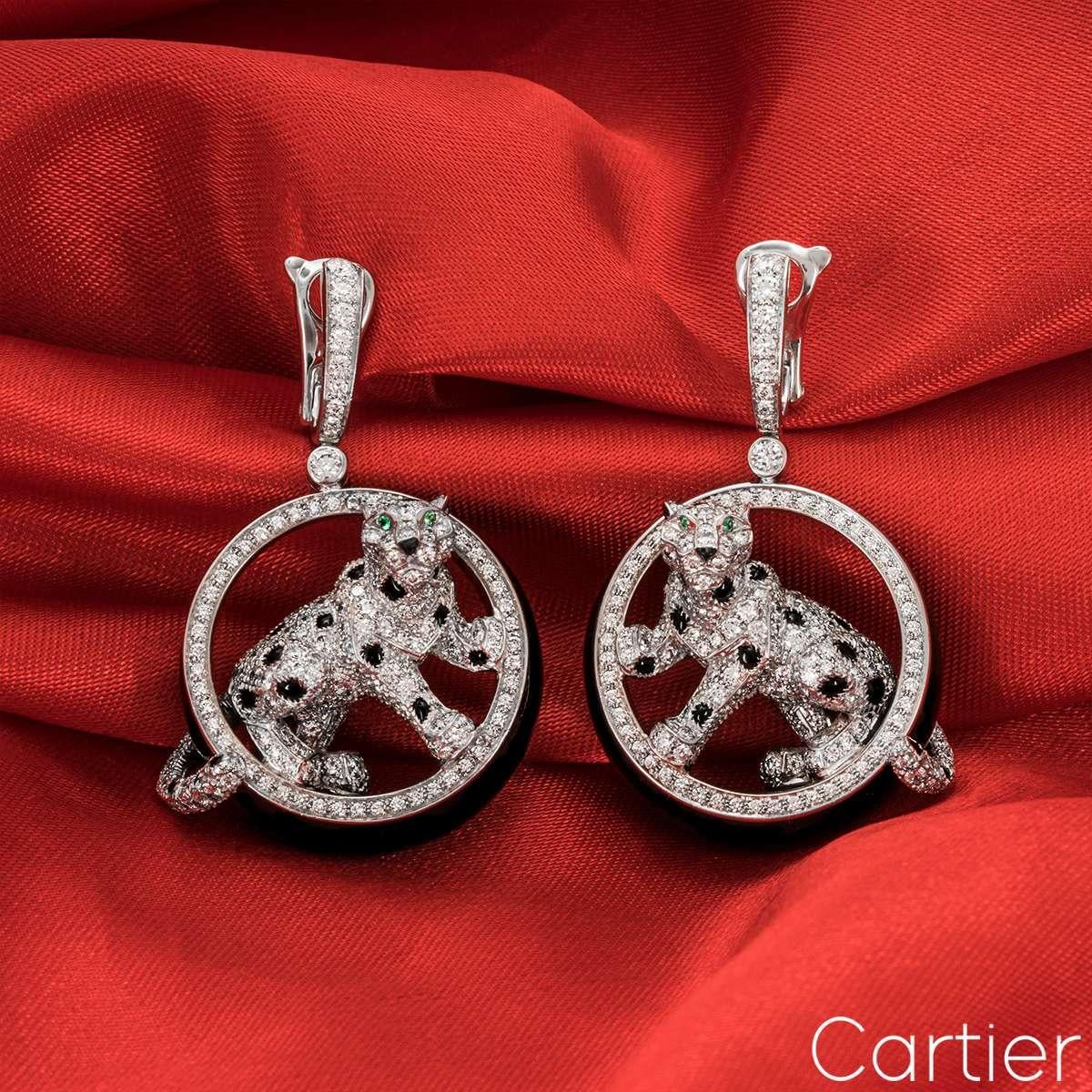 An exceptional pair of 18k white gold diamond and multi-gemstone earrings by Cartier from the Panthère de Cartier collection. The drop earrings feature a panther motif set between a circle motif comprising of 52 pave set round brilliant cut diamonds