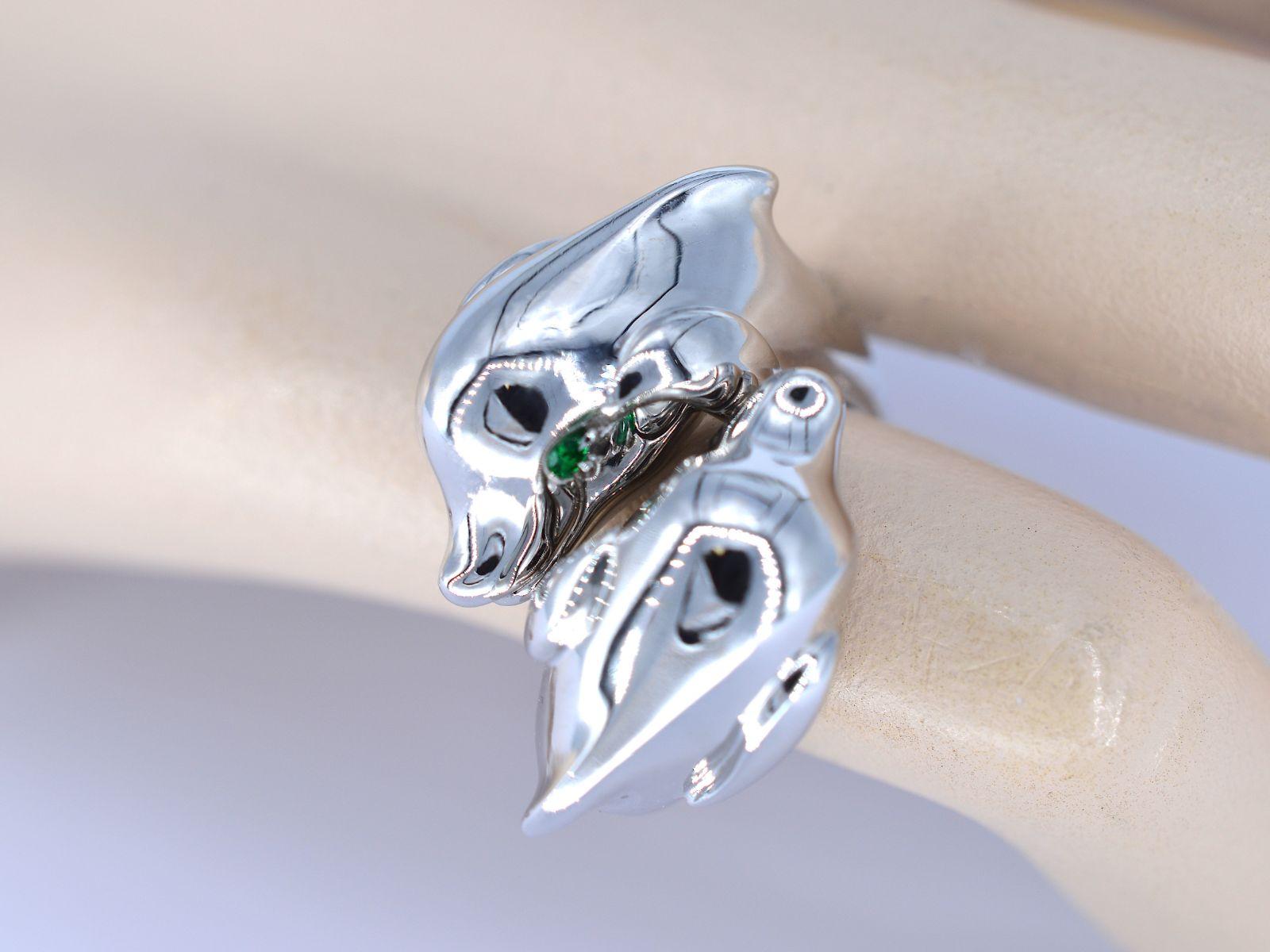 A charming Cartier ring featuring two intricately designed dolphins, adorned with emerald eyes. This delightful ring, captures the playful spirit of dolphins in a luxurious piece of jewelry. Crafted from exquisite 18K white gold 750 and weighing