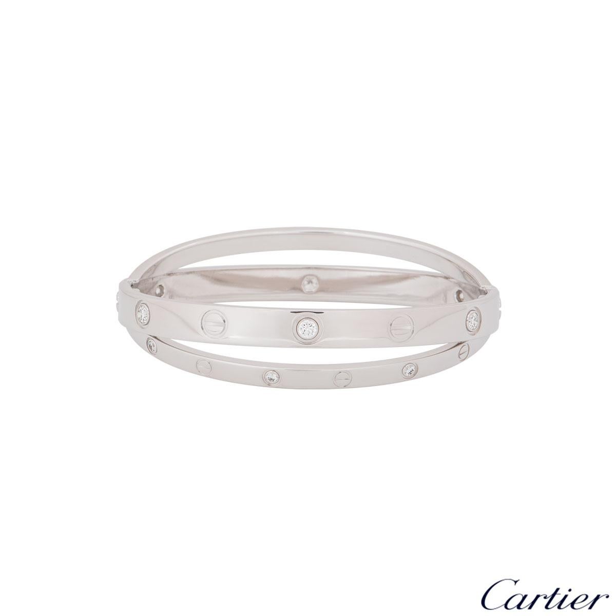 An iconic 18k white gold half diamond double Cartier bracelet from the Love collection. The double bangle features the iconic screw motif alternating with 12 round brilliant cut diamonds displayed around the outer edge. The bracelet is a size 16 and