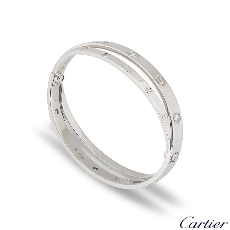 An iconic 18k white gold half diamond double Cartier bracelet from the Love collection. The double bangle features the iconic screw motif alternating with 12 round brilliant cut diamonds displayed around the outer edge. The bracelet is a size 17 and