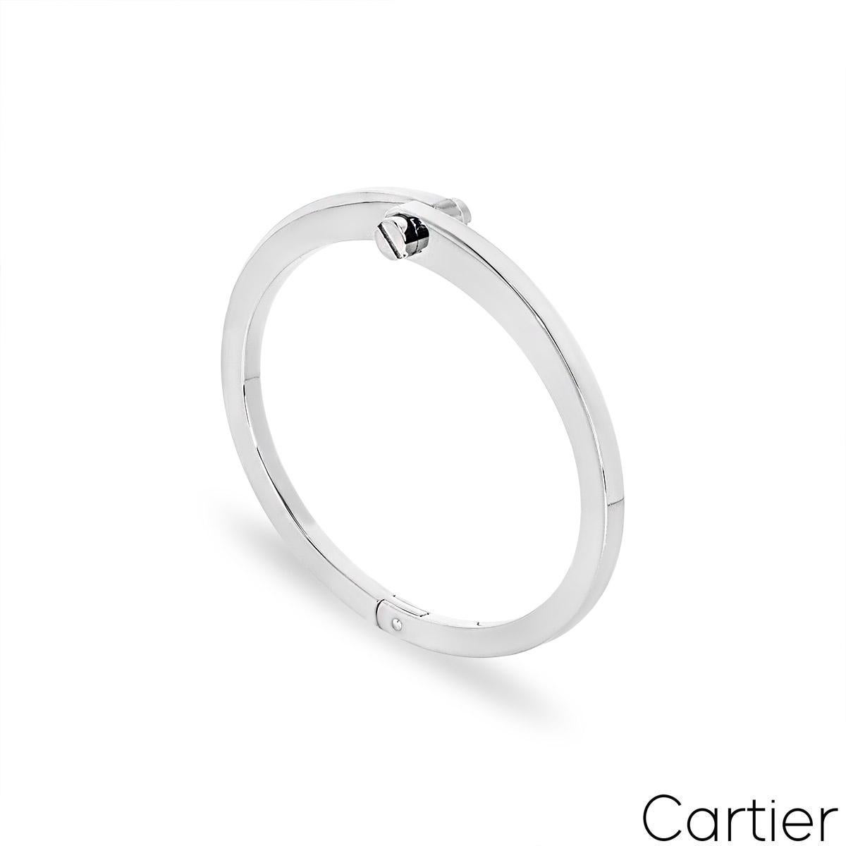 Un bracelet Cartier en or blanc 18 carats de la collection Menotte. Le bracelet est assemblé au centre par deux terminaisons à vis et se termine par une charnière. Elle mesure 12,33 mm de large et s'affine à 3,40 mm. Elle est de taille 17 et a un