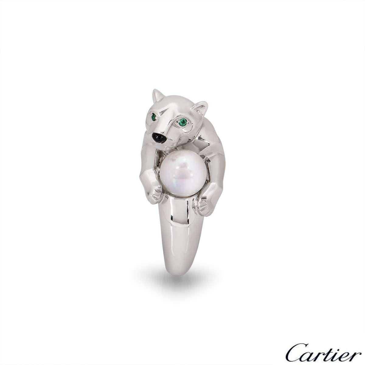 A unique 18k white gold Panthere ring by Cartier. The ring features a Panthere's head with two emeralds set to the eyes and onyx for the nose. The Panthere is clutching a cultured pearl between the paws. The ring size is a UK L / EU 51 / US 6 and