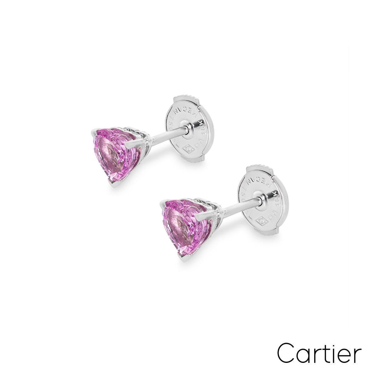A lovely pair of 18k white gold pink sapphire stud earrings by Cartier. The earrings each feature a heart shaped pink sapphire set in a three prong mount with an approximate total weight of 1.20ct, displaying a vibrant pink hue. They finish with