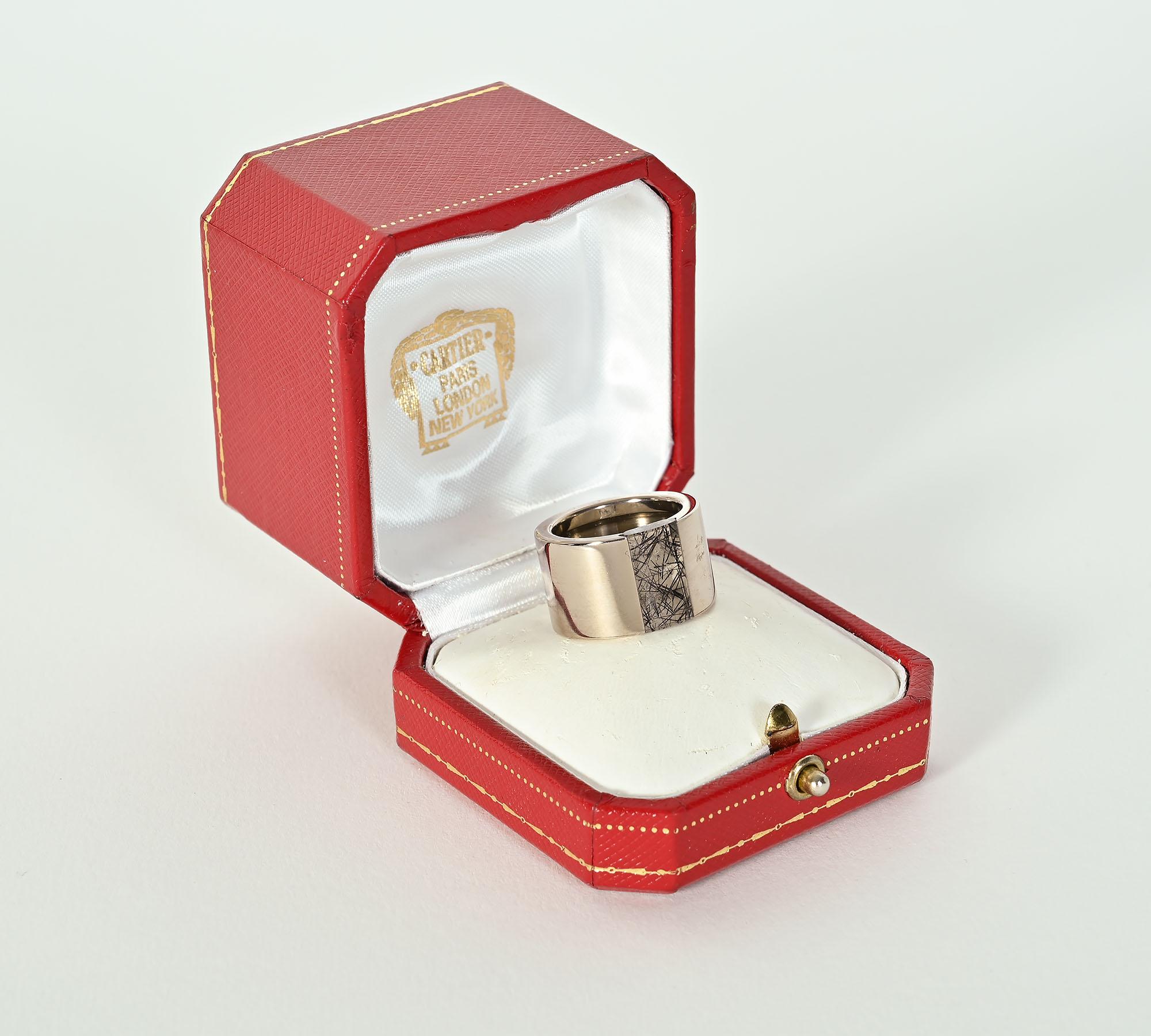 Unusual wide band ring by Cartier. It is done in 18 karat white gold with a slice of rutilated quartz in the center that measures 5/16