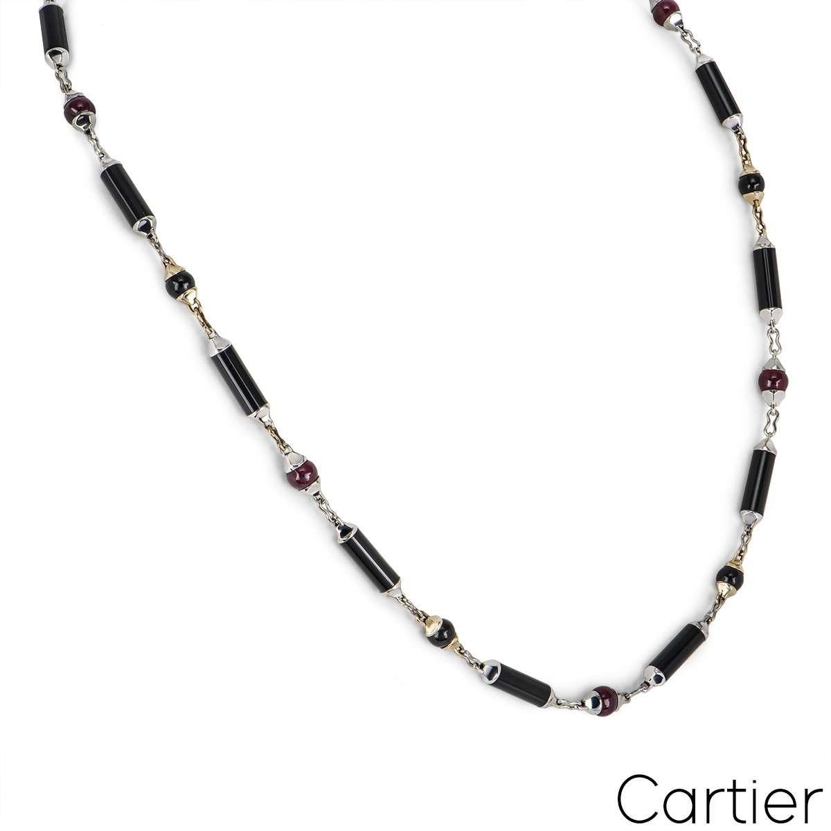 A unique 18k white and yellow gold onyx and ruby Cartier necklace from the Le Baiser Du Dragon collection. The necklace comprises of 13 cylinder bar motifs all featuring onyx inlays, alternating in between we have 6 cabochon cut rubies set in white