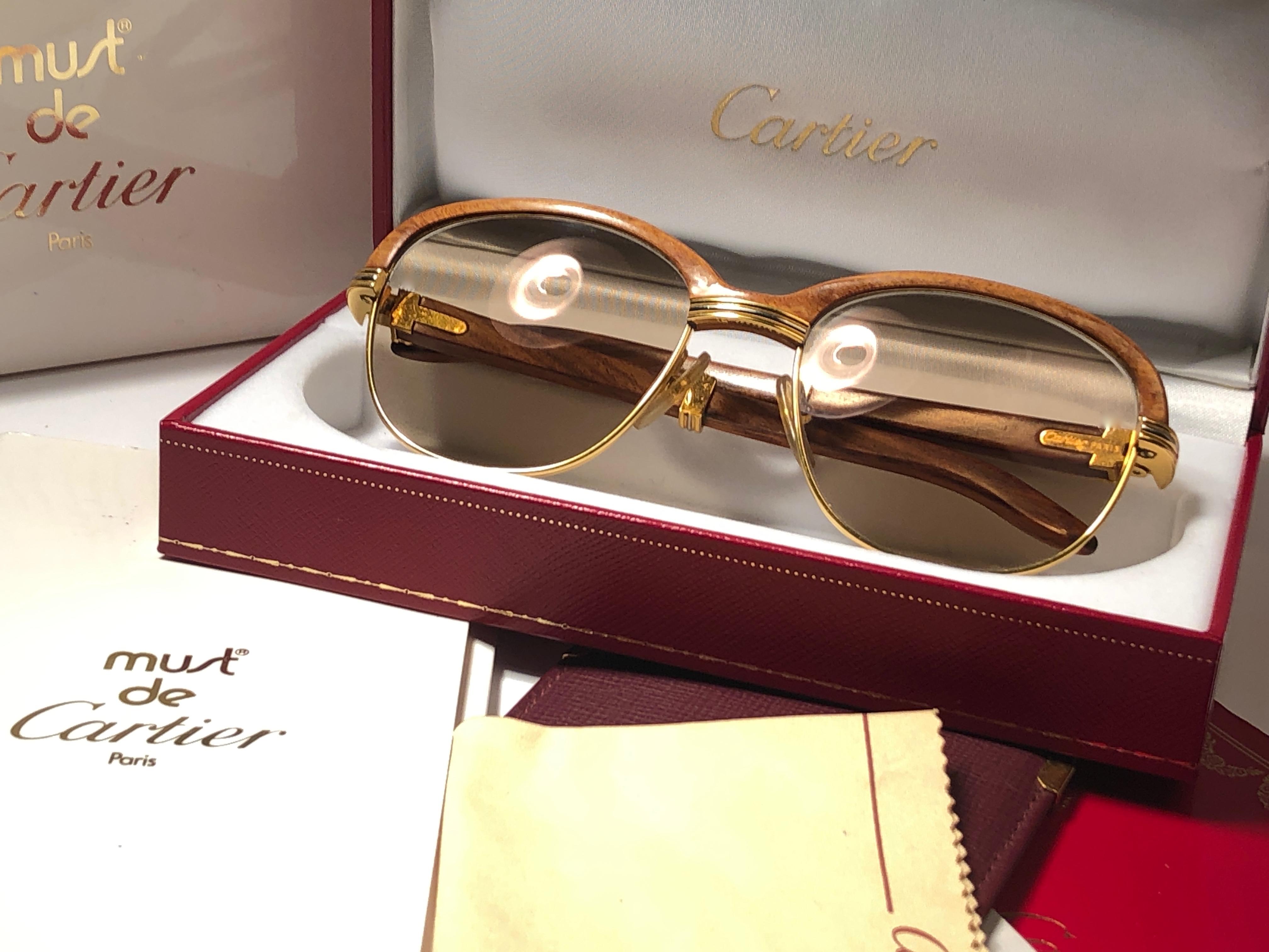 Original 1990 Cartier Malmaison Sonnenbrille aus hellem Bananenholz mit honigbraunen Cartier Gläsern (UV-Schutz). 
Vorderseite und Seiten in Gelb- und Weißgold und mit der berühmten Holzfront. Auch die Tempel sind aus Palisander, kombiniert mit