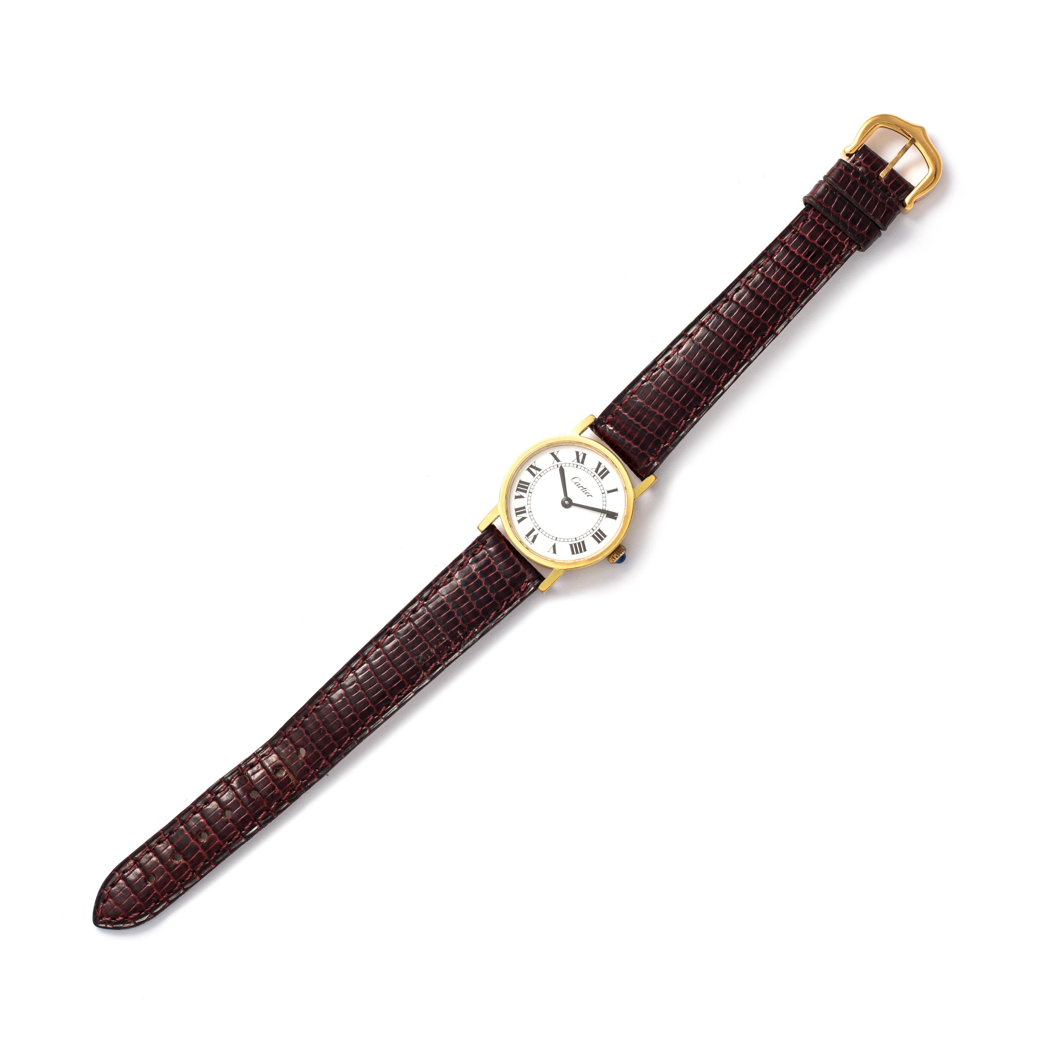 Cartier. Solo collection. Gold-plated metal wristwatch, round shape, white background and Roman numerals.
Bordeaux leather strap and pin buckle. Cabochon-cut sapphire on the winding.
Quartz movement. Signed Cartier. 
Diameter of the dial: 23.00 mm.