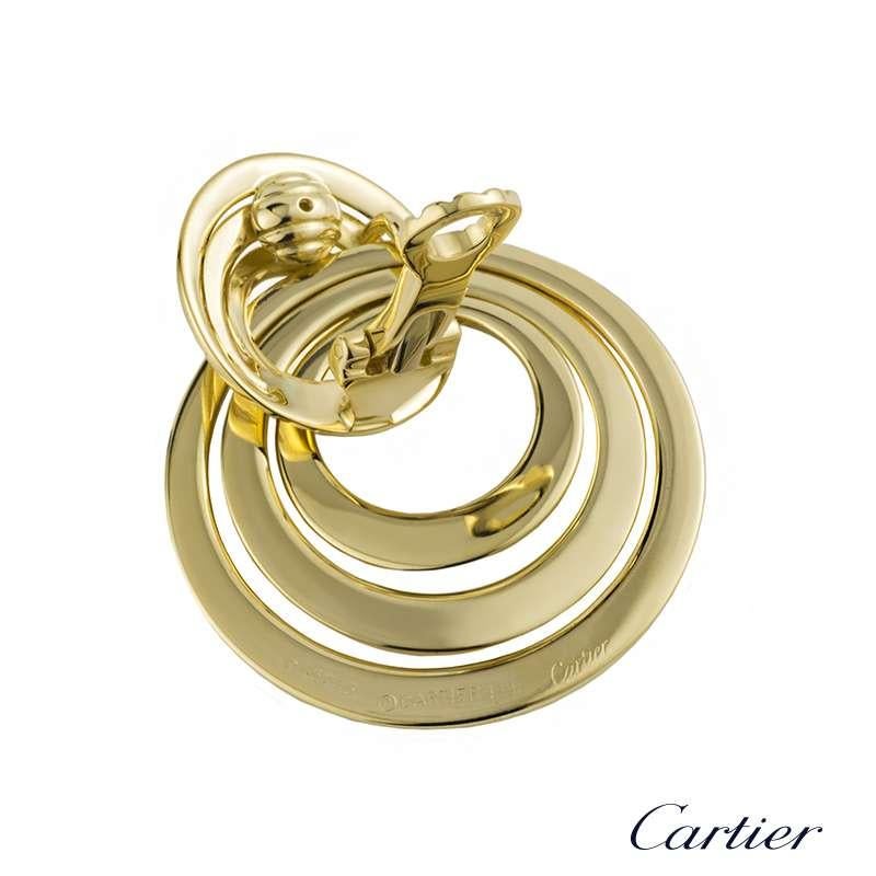 An elegant pair of 18k yellow gold circular earrings by Cartier. The earrings comprise of a concentric circular drop design graduating in a triple row combination from small to large with a simple hinged clip fitting. The earrings are signed Cartier