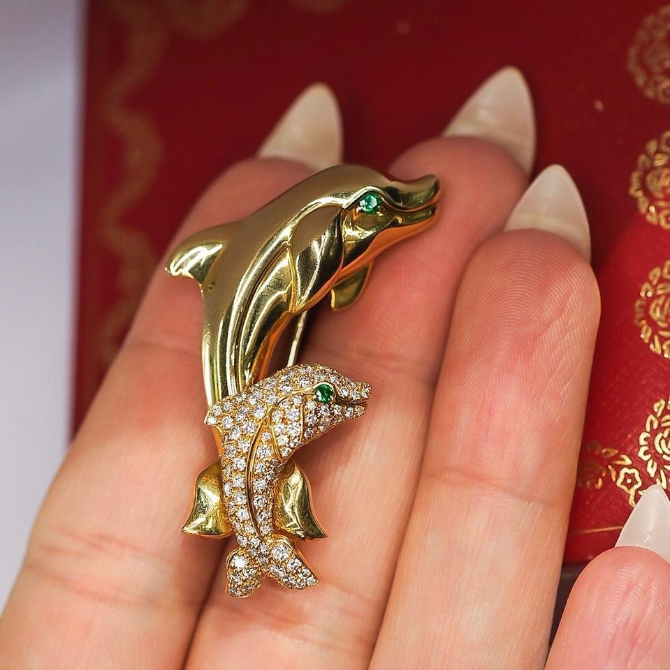 Cartier
Yellow Gold Diamond Dolphins Emerald Eyes Pin Brooch

CARTIER DOLPHIN BROOCH
Designed as a pair of yellow gold dolphins, the smaller one set with diamonds, both with emerald eyes. Designed as two dolphins, one pave-set with brilliant-cut