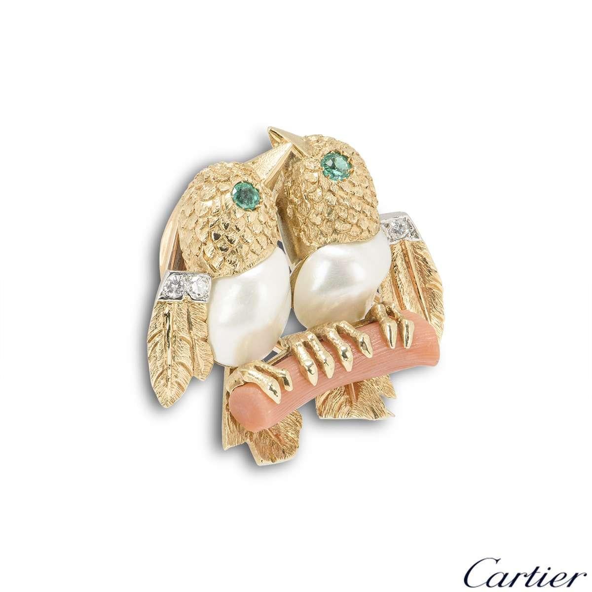 A charming 18k yellow gold Lovebird brooch by Cartier. The birds are made from textured yellow gold and pearls, with emeralds set as the eyes and 3 round brilliant cut diamonds set in the wings, perched on a coral branch. The brooch measures 2.5cm
