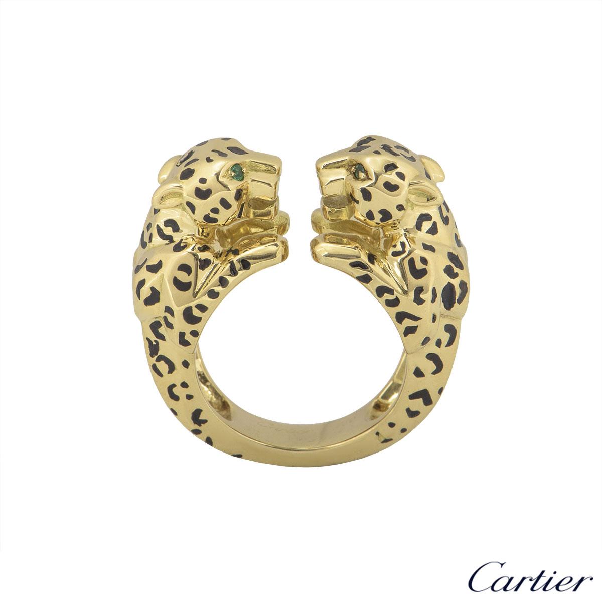 A beautiful 18k yellow gold and enamel ring by Cartier from the Panthere De Cartier collection. The ring is composed of two panthere head motifs beside each other set with bold enamel spots and are complemented with two round emeralds set as the