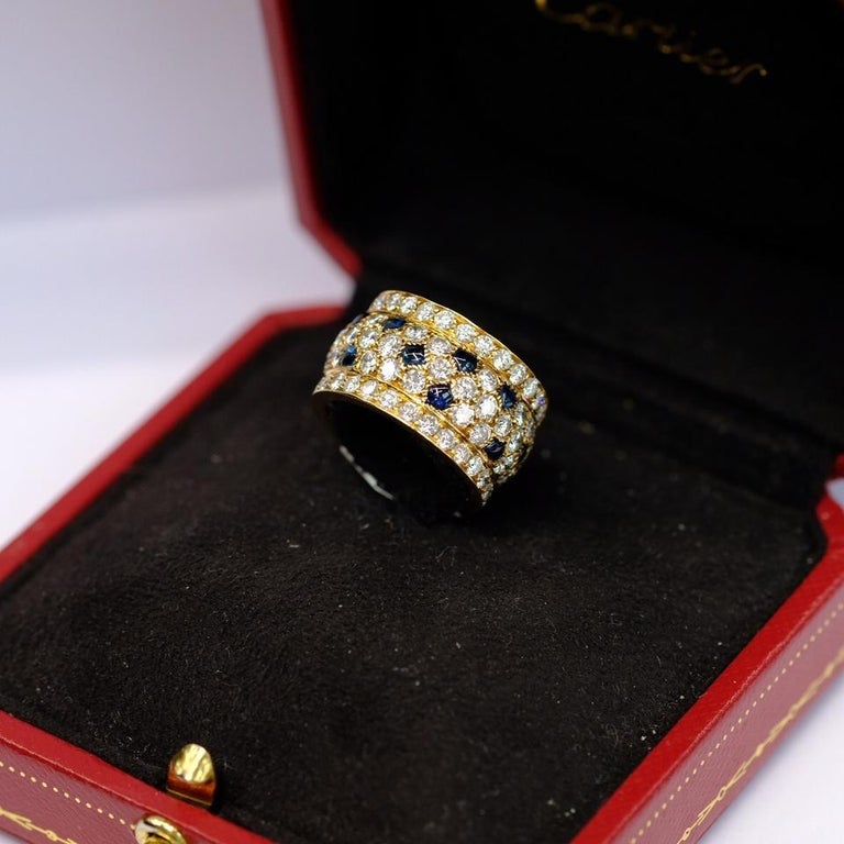 Diamond and sapphire 'Nigeria' ring, Cartier, France.
The band ring set with round diamonds weighing approximately 5.60 carats, with buff-top sapphire accents,
Ring size is 6.5 to 6.75.
Signed Cartier, with French assay and maker's marks.
With the