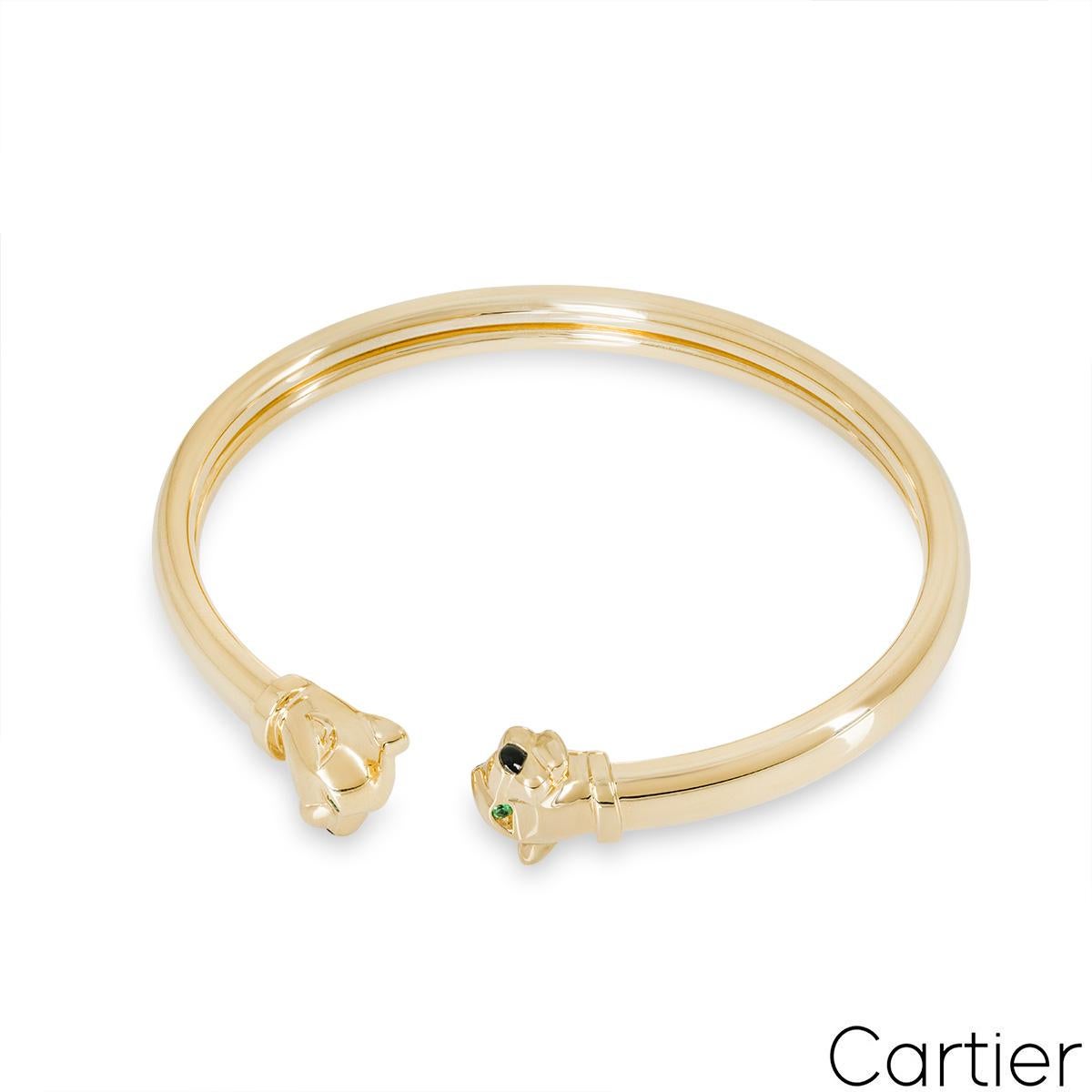 Ein hübsches Manschettenarmband aus 18 Karat Gelbgold von Cartier aus der Panthère de Cartier Kollektion. Die Manschette besteht aus zwei sich gegenüberliegenden Pantherköpfen mit Tsavorit-Augen und einer Onyxnase. Das Armband passt für eine