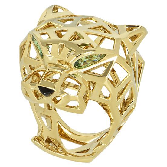 A striking 18k yellow gold Cartier dress ring from the Panthere De Cartier collection. The ring comprises of an open work panther motif with 2 pear cut tsavorite garnets for eyes and an onyx nose. The ring measures 3.30cm in height, is UK size Q & 
