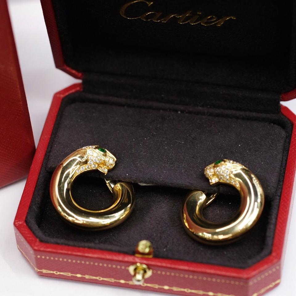 Each polished hoop terminating with a panther's head accented with brilliant-cut diamonds, with pear-shaped emerald eye.

With original red Cartier box.

Beautiful earrings from one of the worlds most coveted jewelry houses.

Material: 18K Yellow