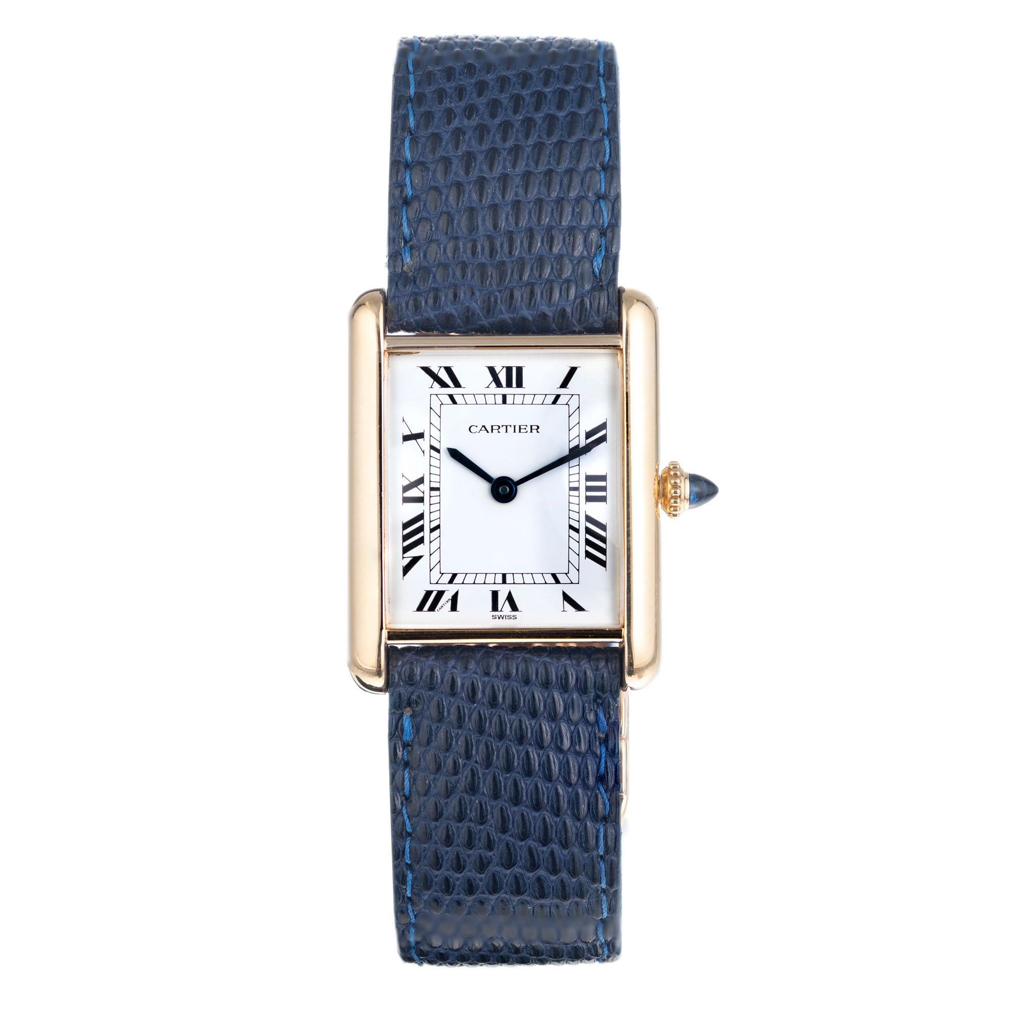 Vintage 1970's Cartier tank Louis manual wind wristwatch. Original white dial with Roman Numerals. 18k yellow gold Cartier deployant buckle with blue Cartier band.

Length: 30.24mm
Width: 23 mm
Width at case: 18mm
Case thickness: 6.59mm
Band: blue