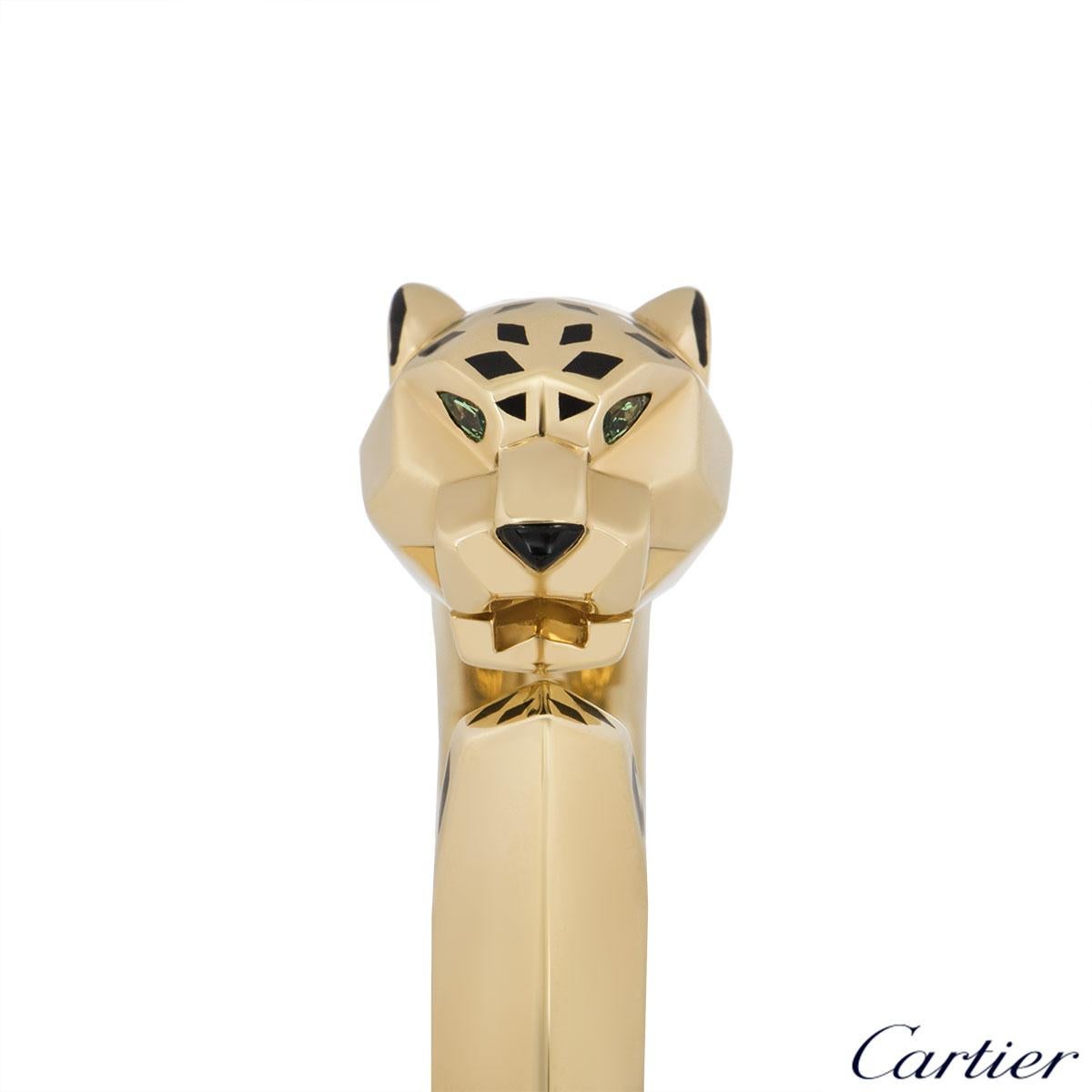 An 18k yellow gold tsavorite, onyx and black lacquer bracelet by Cartier from the Panthere De Cartier collection. The bracelet features the iconic panther head motif set with 2 tsavorite eyes, onyx nose complimented by black lacquer detailing. The