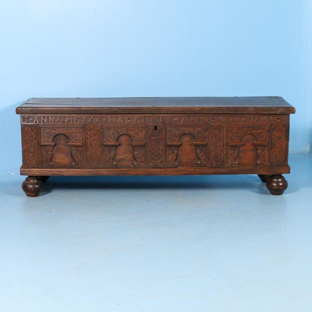Carved antique oak coffer trunk from Denmark dated 1757, with a carved paneled front, original iron handles and strap hinges, all resting on bun feet.

This item is part of our “un-restored” collection and is being sold in 