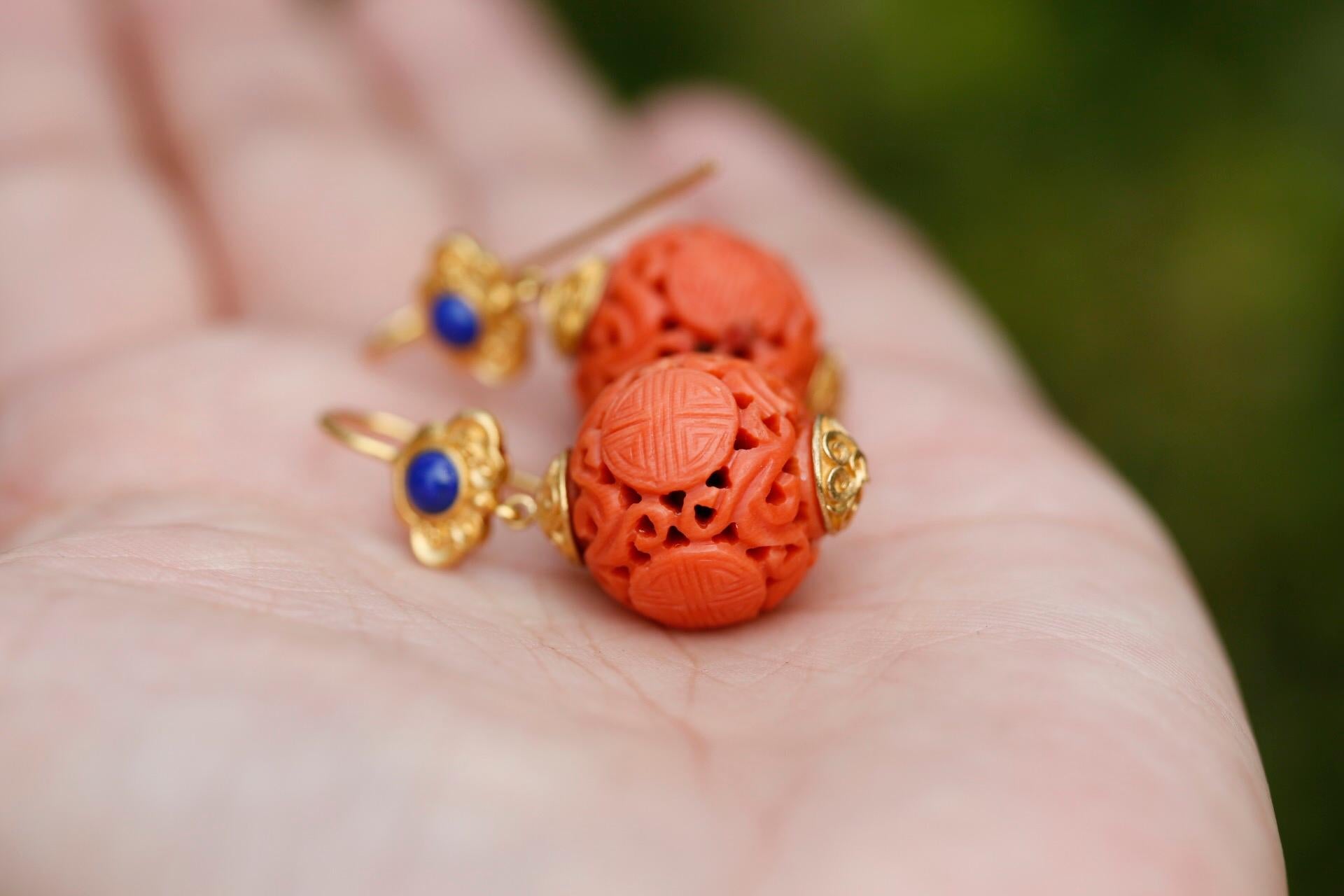 Exquisitely carved 19th century antique coral beads, measuring roughly 12mm each, hang below deep blue lapis lazuli pieces measuring roughly 2.8mm. Around the lapis is Chinese style scrolling in rich yellow gold. A final touch of gold finishes these