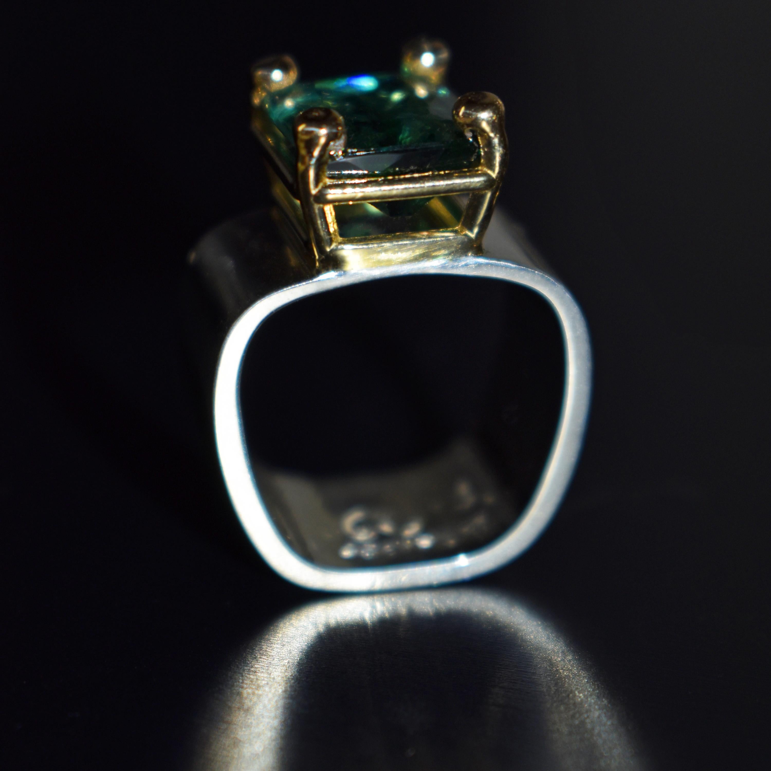 Beautiful hand-carved, rectangular cushion cut 5.39 carat greenish blue Indicolite Tourmaline set in a 14k yellow gold four prong basket on a sterling silver wide, square ring band. Ring is size 7. Gorgeous, carved vine design in this one-of-a-kind