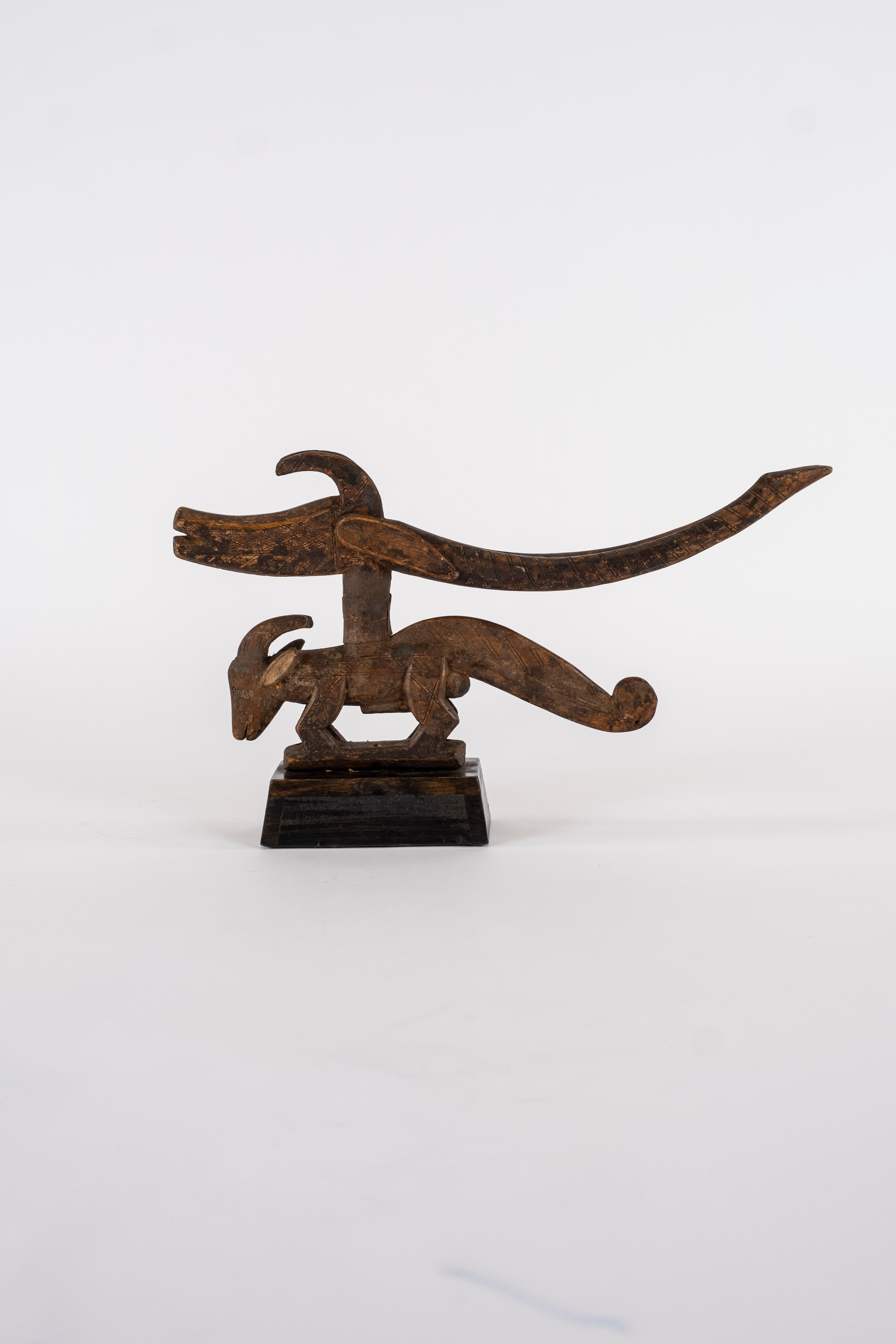 Copricapo astratto mitologico intagliato di antilope montato su supporto in Wood. Questi motivi simboleggiano l'eccellenza nell'agricoltura e i raccolti abbondanti. Le corna delle antilopi indicano la crescita e i formichieri la forza.