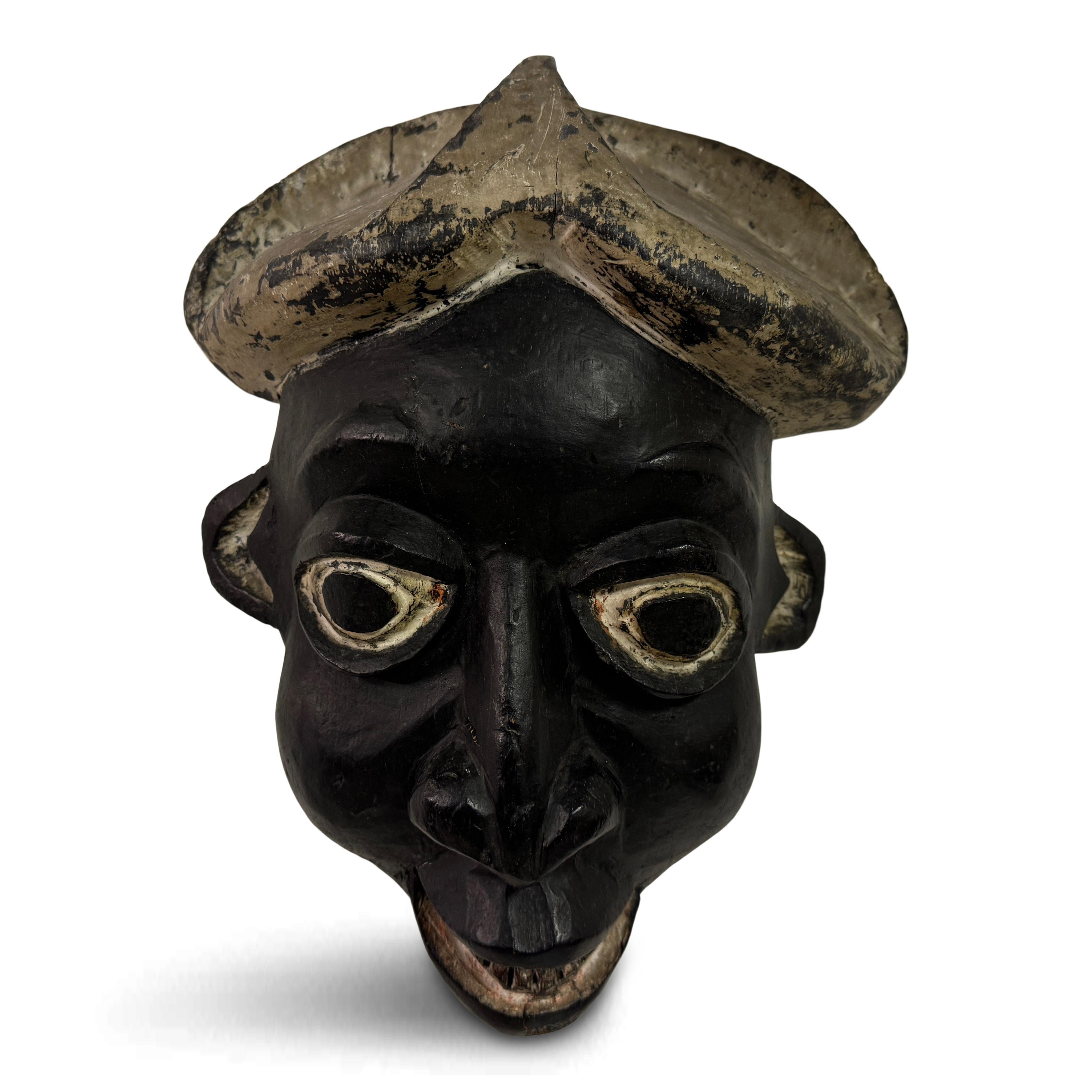 Questa immagine raffigura una maschera tradizionale africana, caratterizzata da un design distintivo ed espressivo. La maschera è realizzata in legno e presenta una finitura scura,  grazie alle macchie e alla naturale patinatura dovuta all'età e