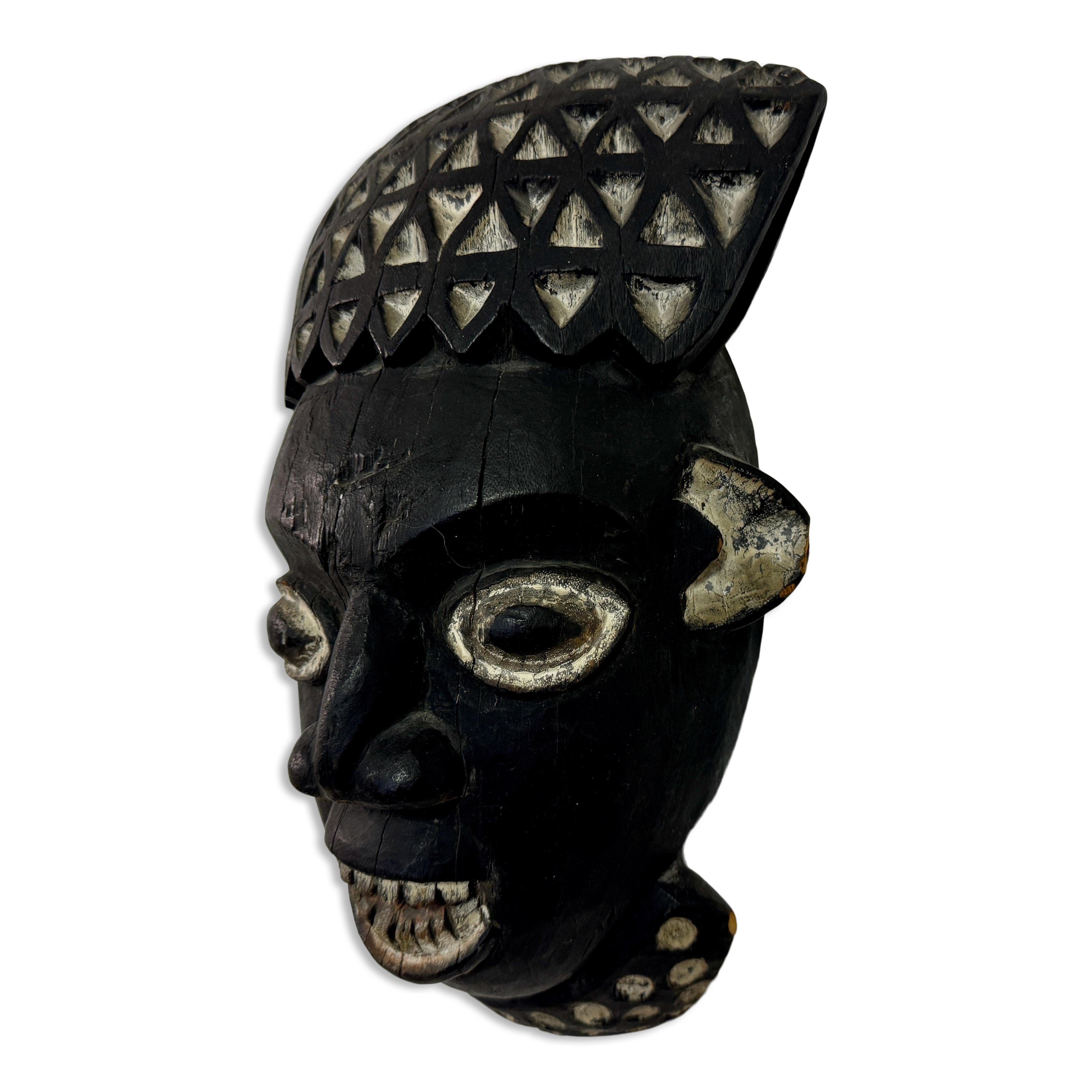 This African mask is characterized by its bold and intricate design, reflecting traditional craftsmanship and cultural significance. The mask is crafted from dark wood, featuring a patina that suggests age and use in various ceremonial contexts. 


